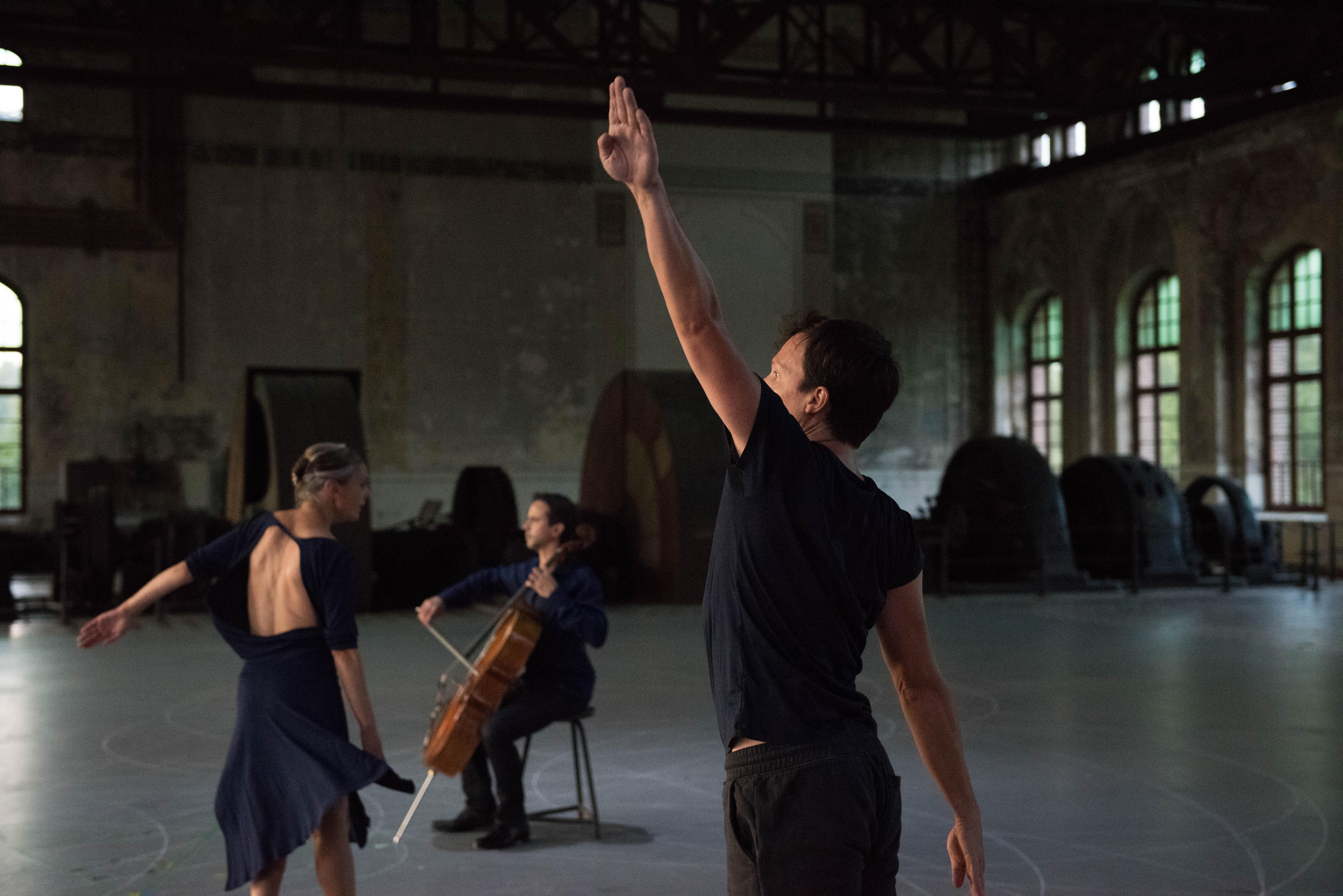 Two dancers moving in front of cellist Jean-Guihen Queyras