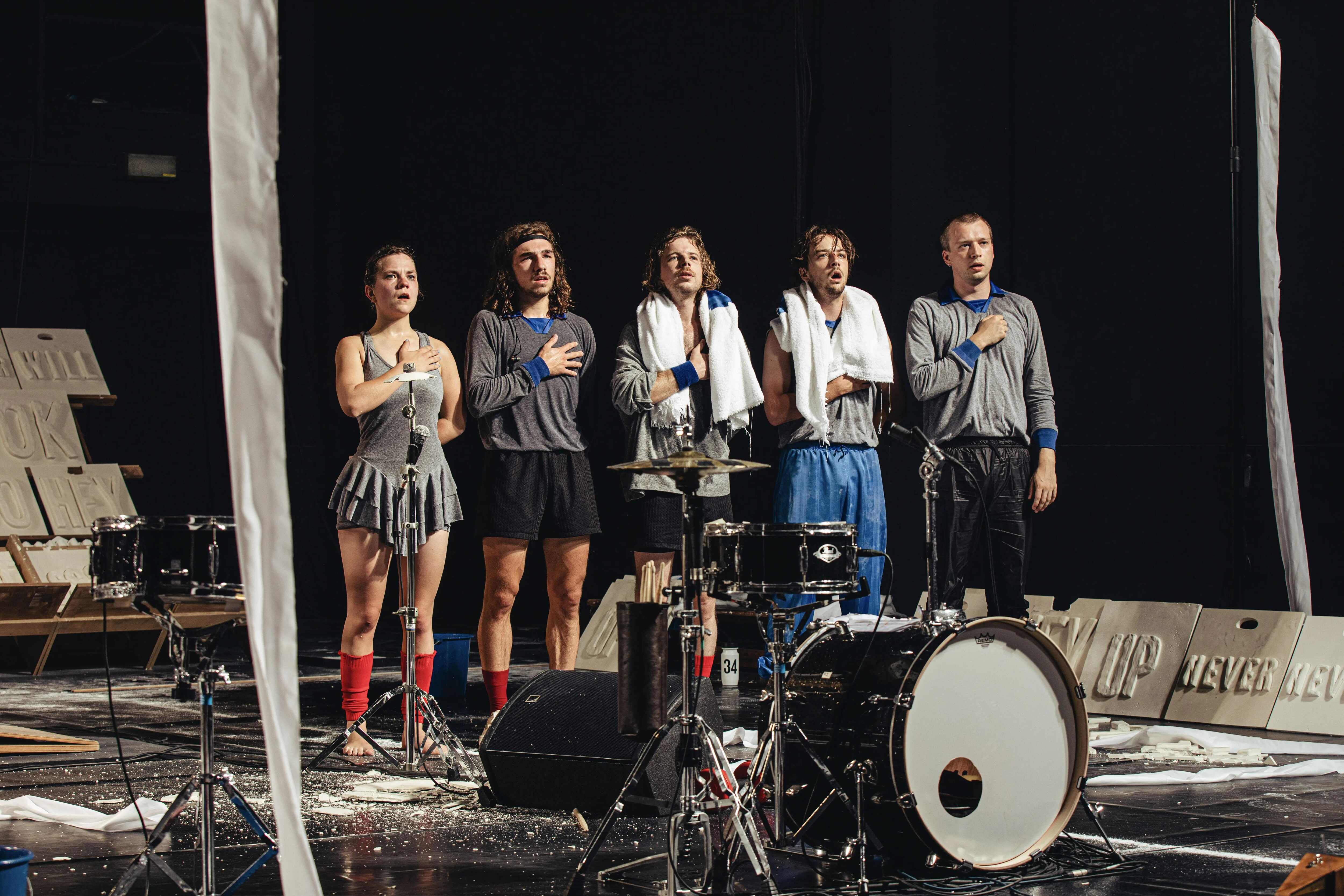 Five people singing with their hand on the heart  