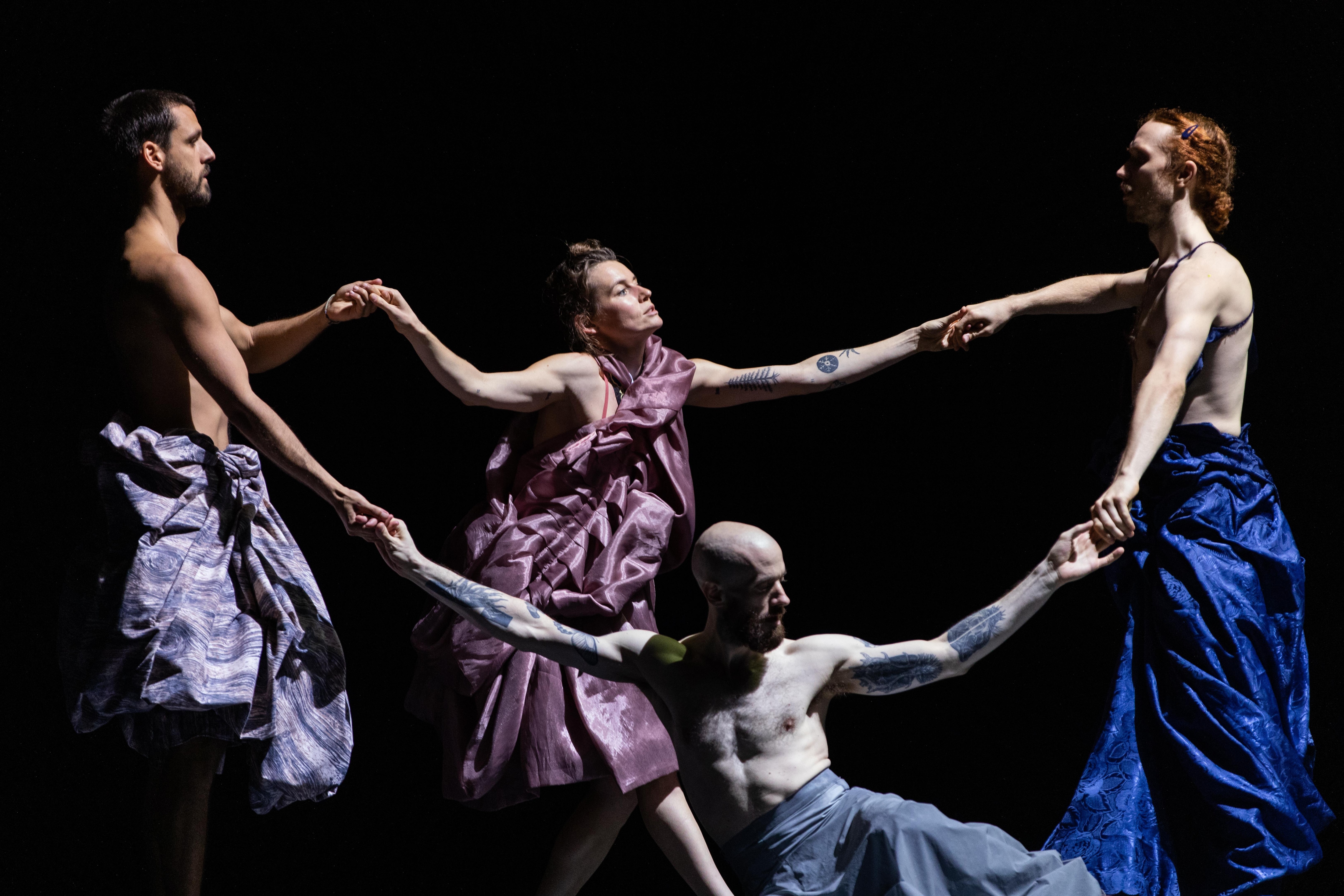 Four dancers holding hands, forming a circle