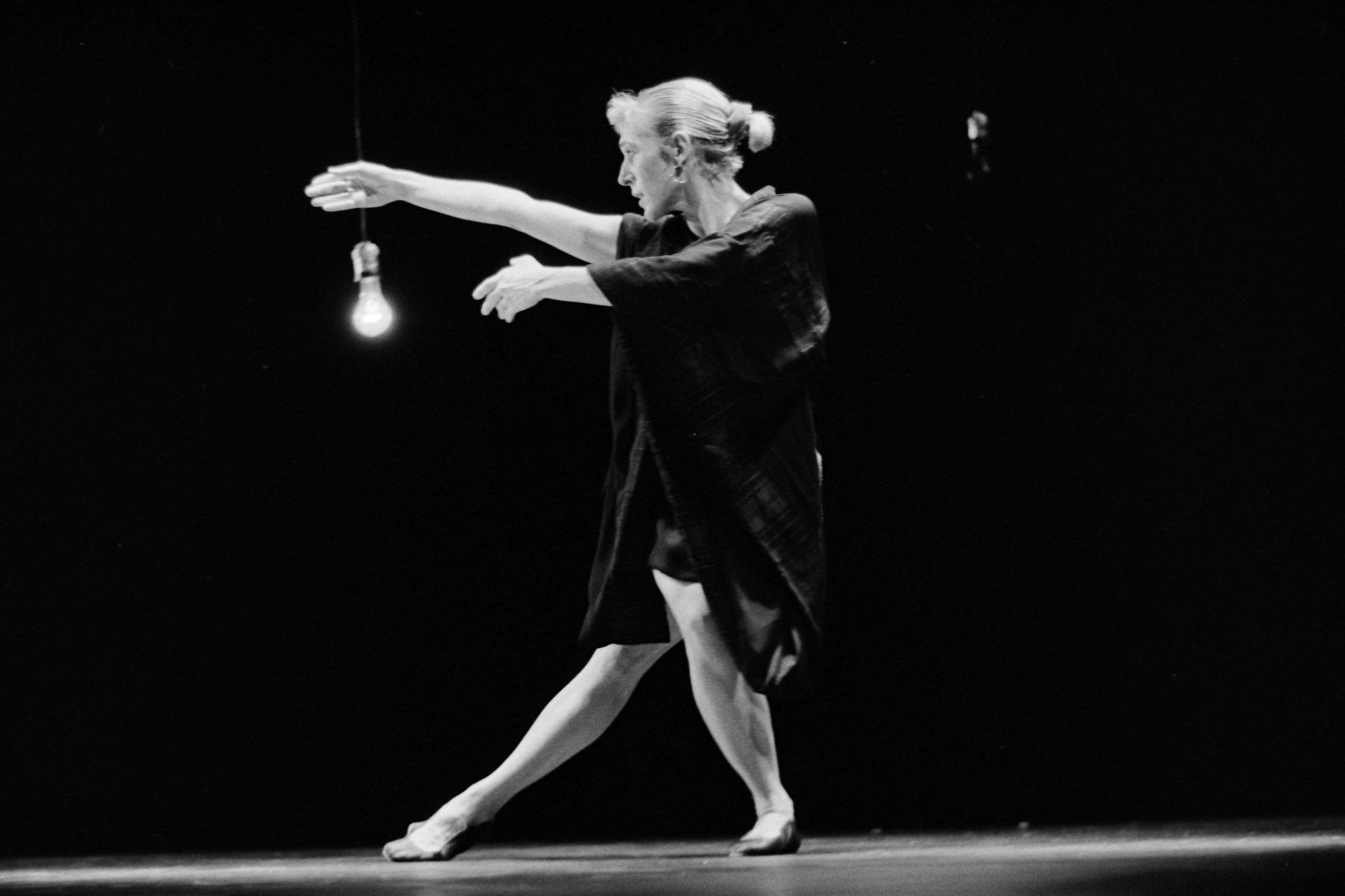 Dancer with arm, leg and gaze to the left of the black and white image