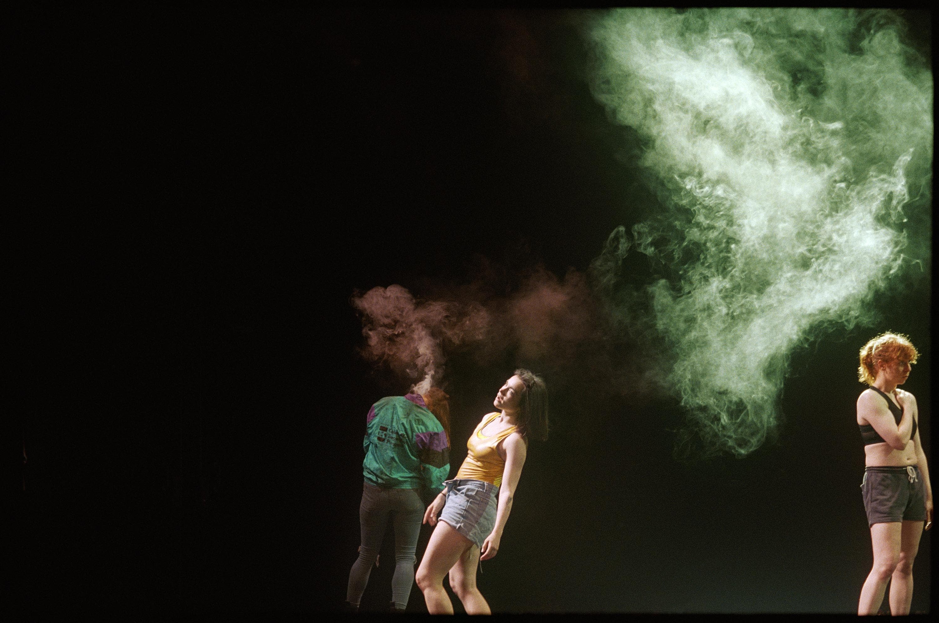 Three dancers in movement during a rehearsal on stage