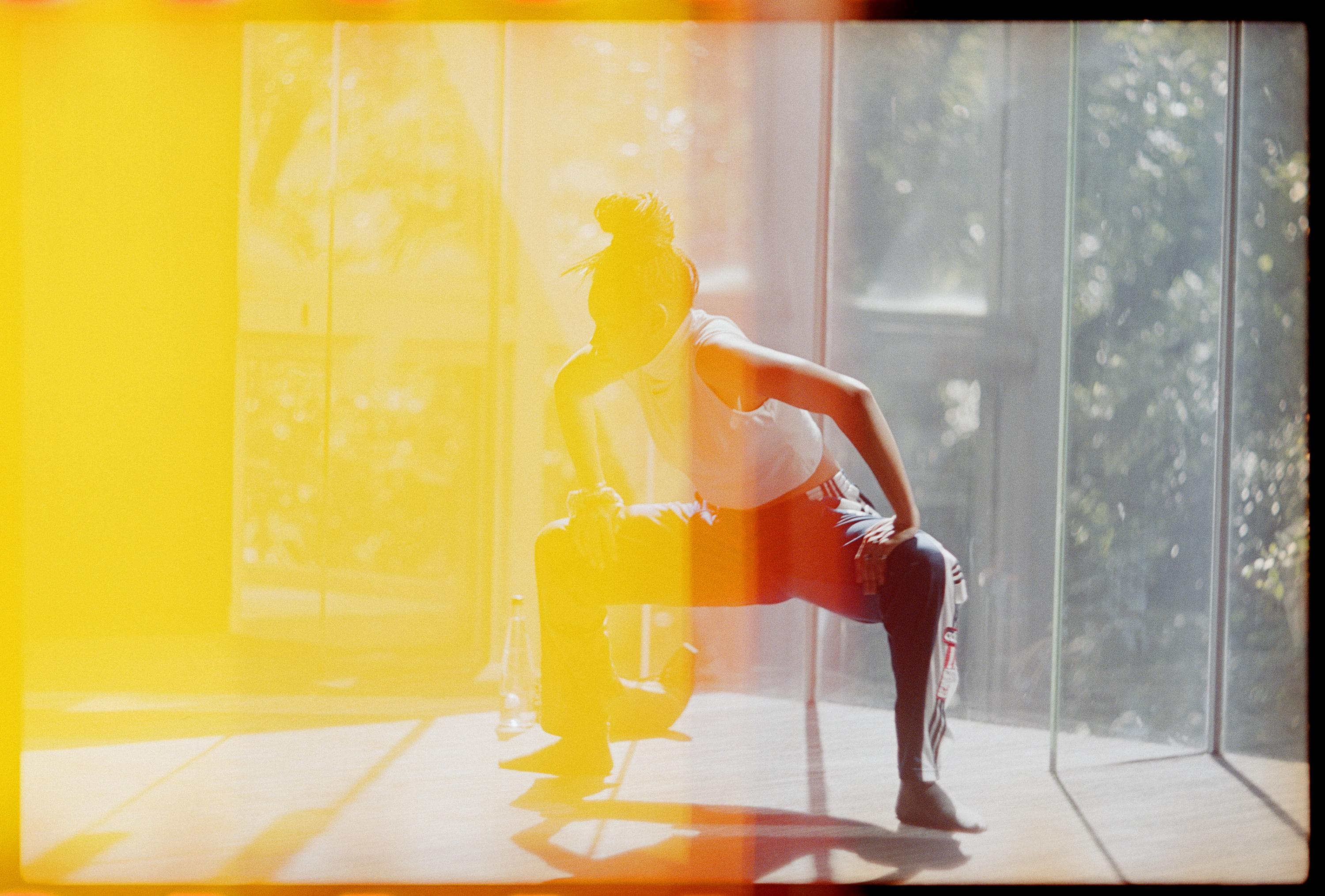 Dancer in the studio, bending her legs, her hands on her thighs.