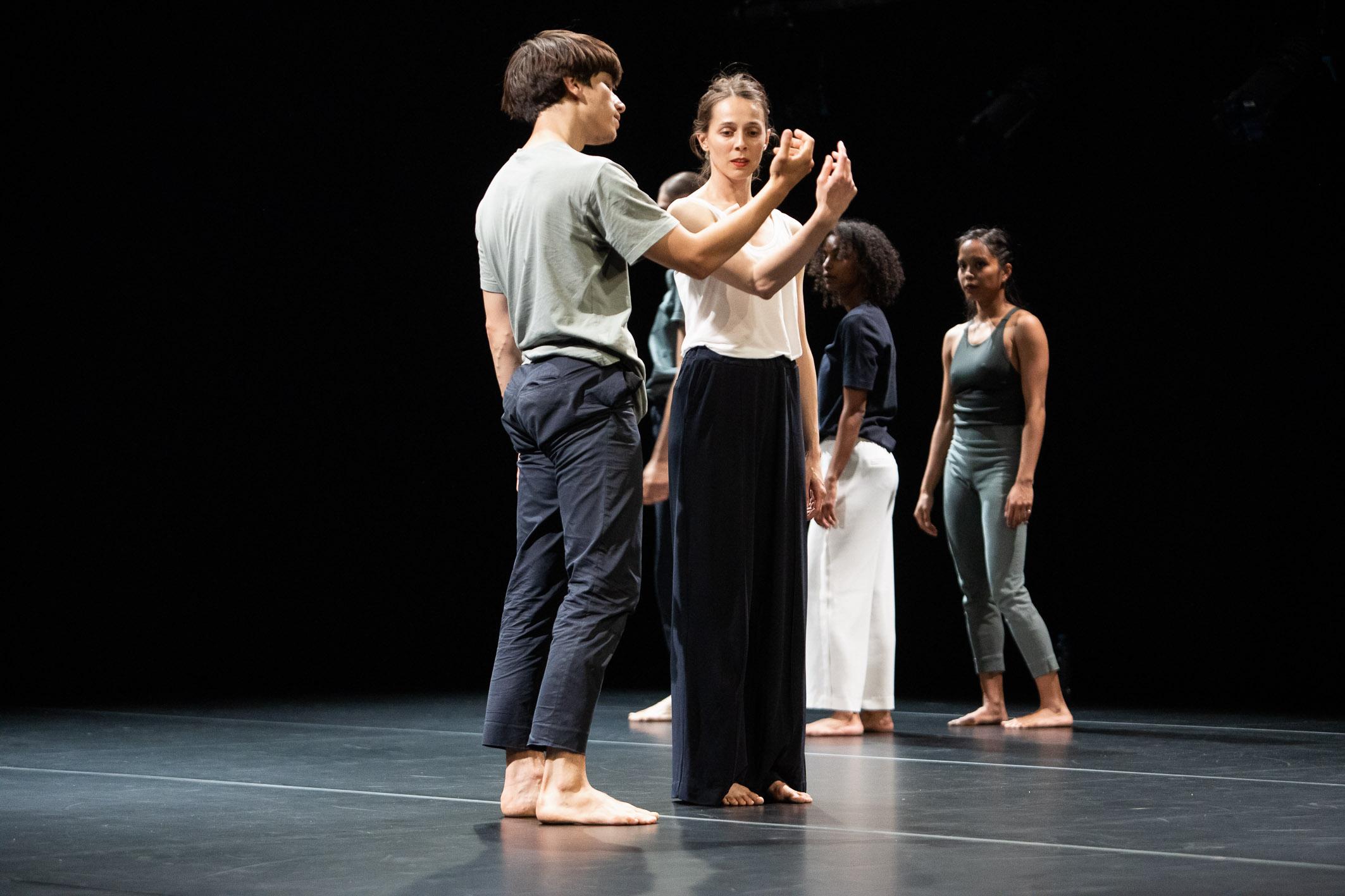 Danseurs se tenant debout dans différentes directions, leur bras levé à l’identique.