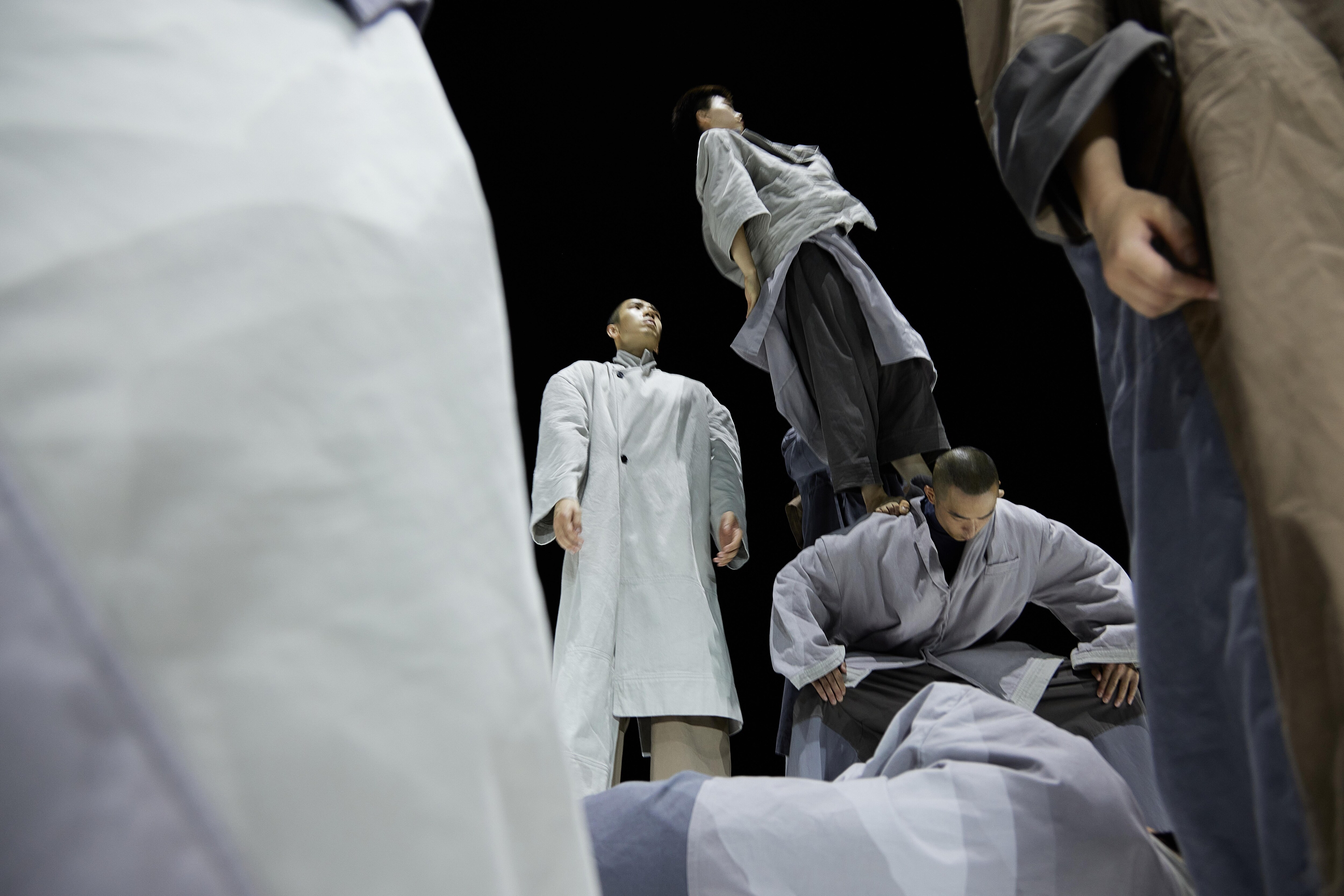Low angle shot of dancers in grey coats.
