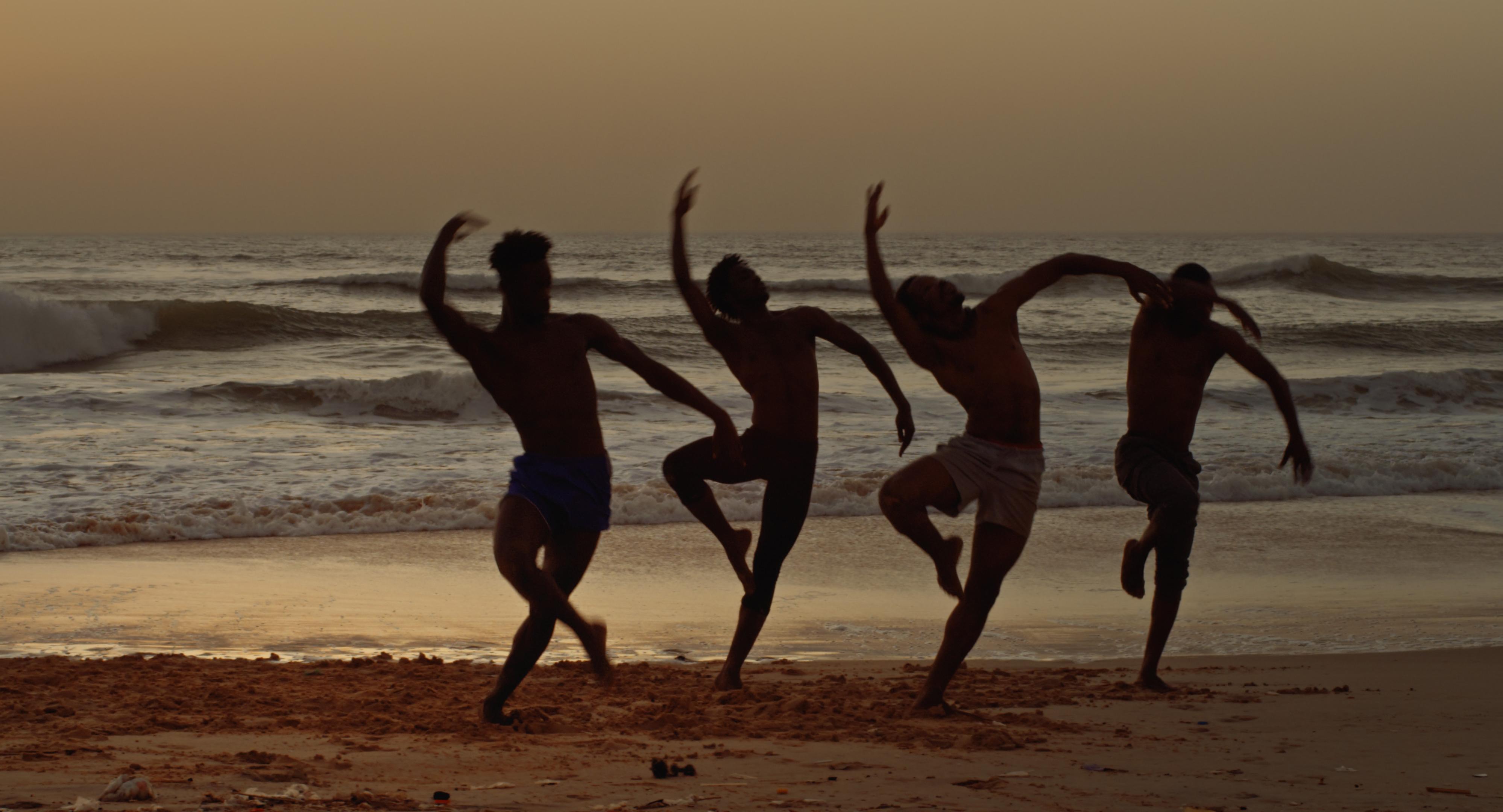 Quatre silhouettes de danseurs exécutant le même mouvement sur la plage au soleil couchant