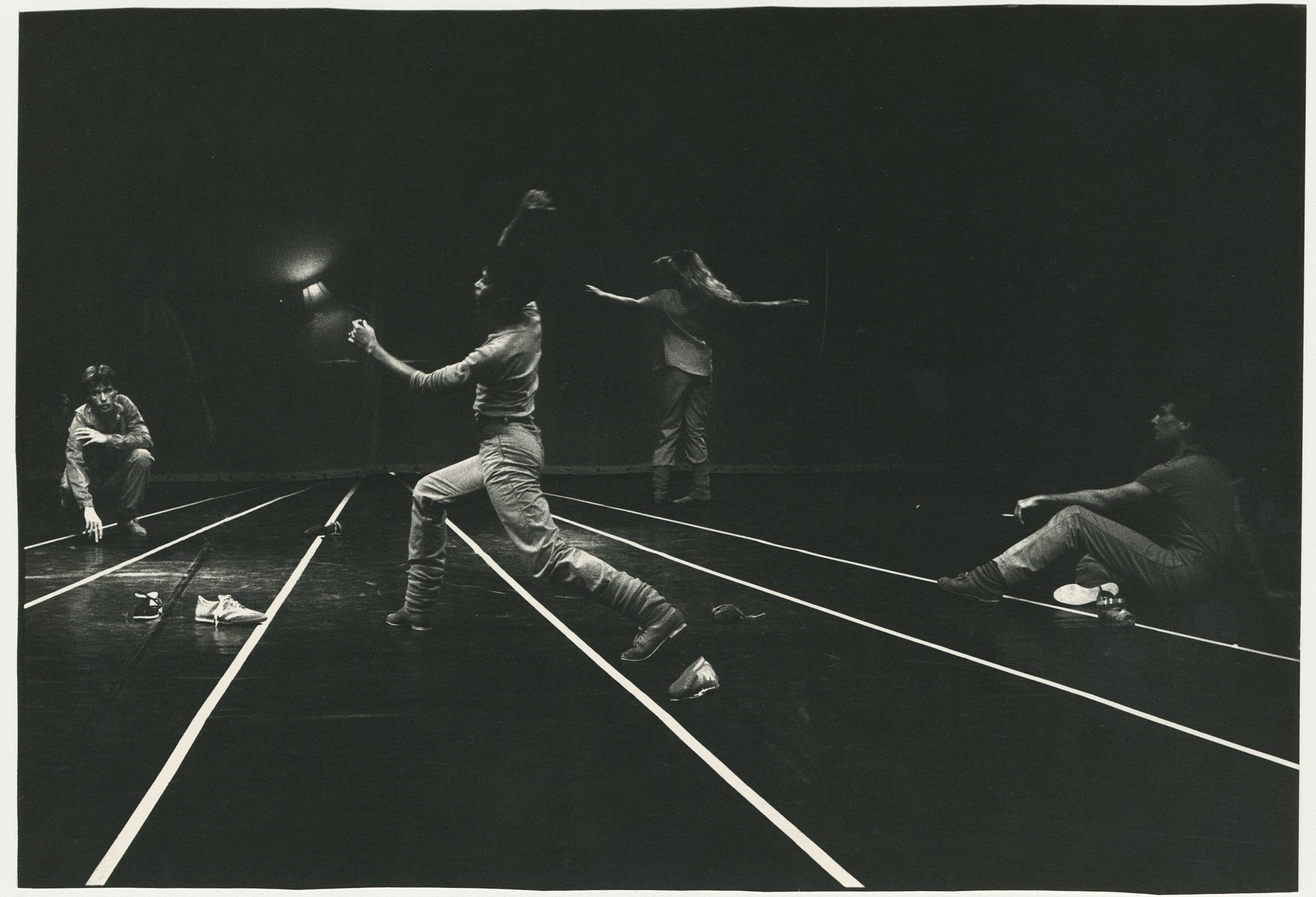 Quatre danseurs en mouvement sur scène – lignes blanches parallèles au sol