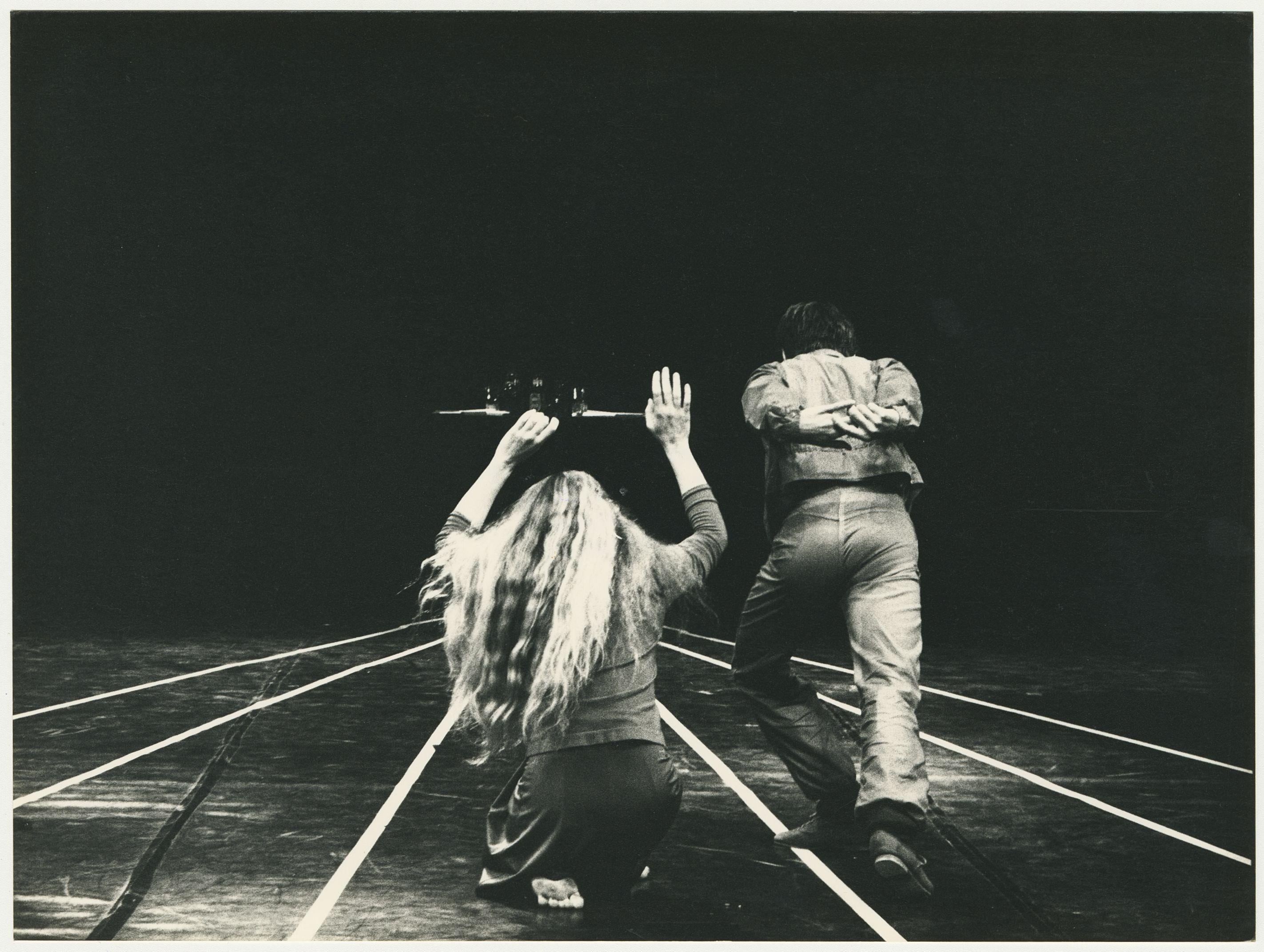 Two dancers with their backs to the floor, facing parallel white lines