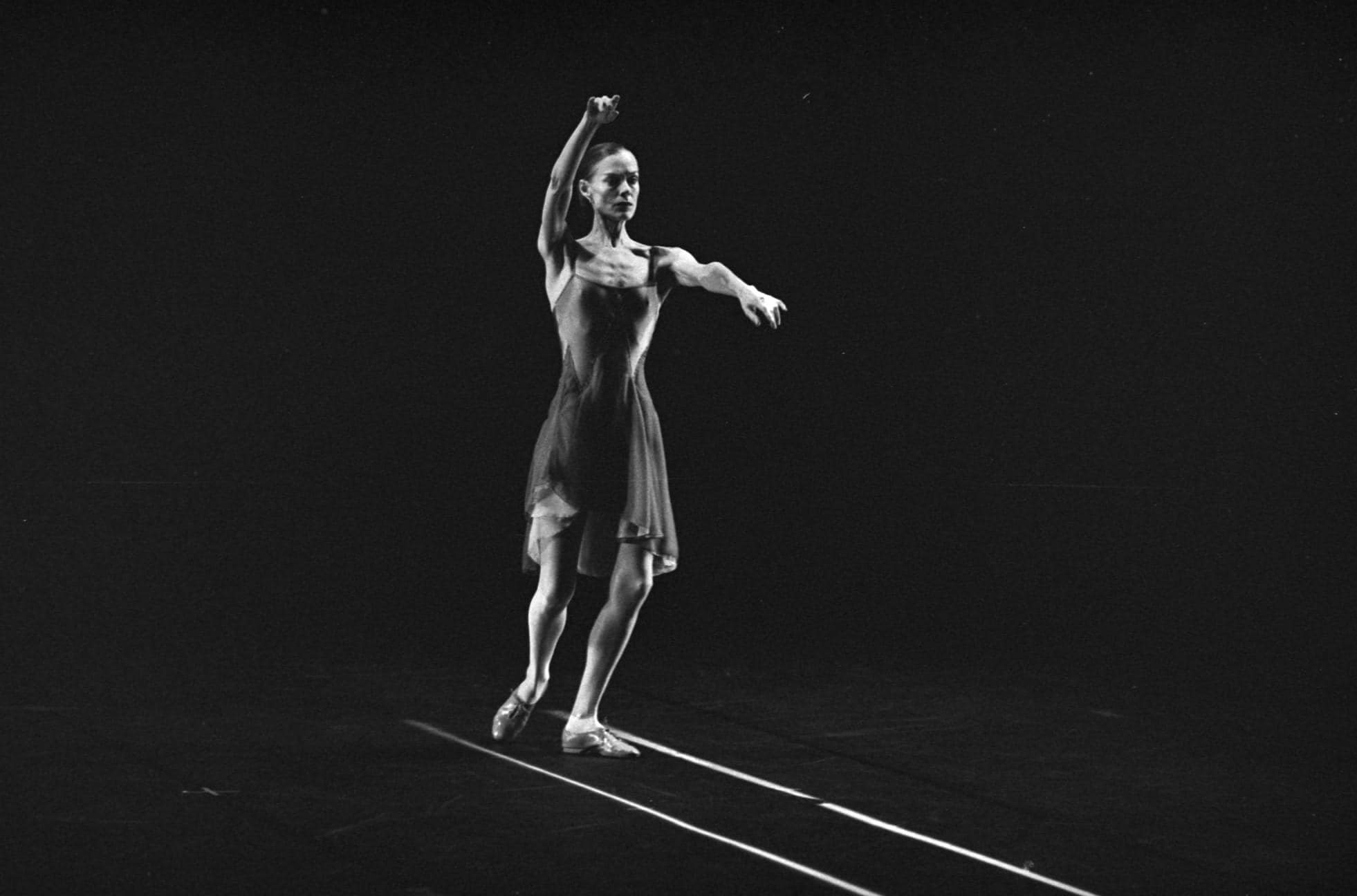 Dancer with arms in the air, following two parallel  lines on the floor.