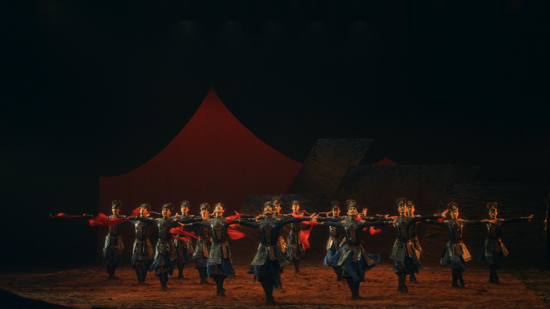 Ensemble de danseurs en tenue traditionnelle avec un foulard rouge.