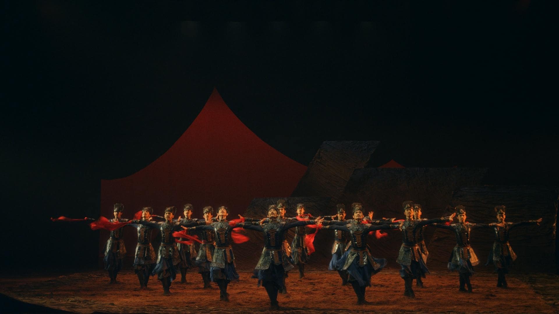 A group of dancers in traditional dress with a red scarf.