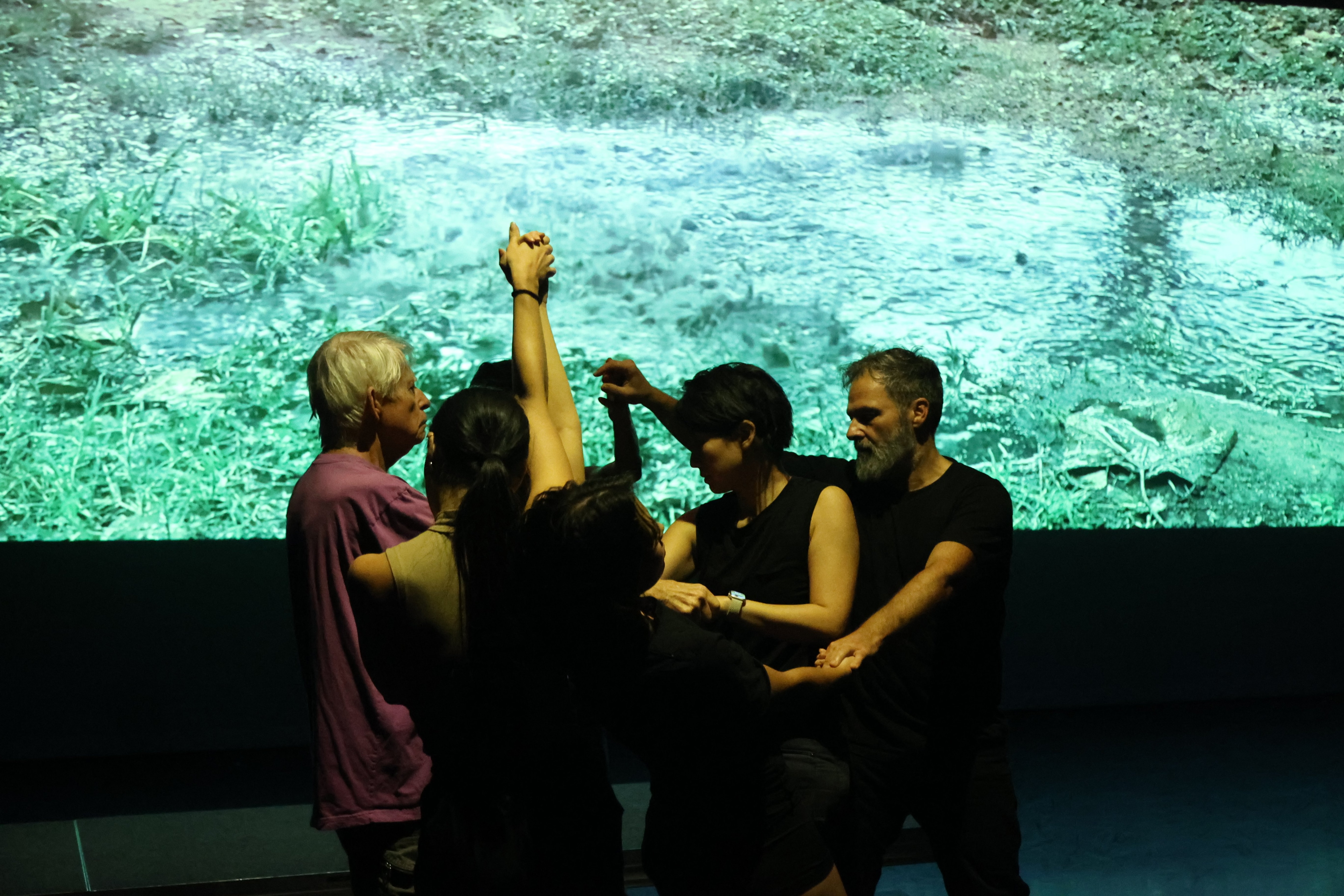 Dancers holding hands - video in the background.