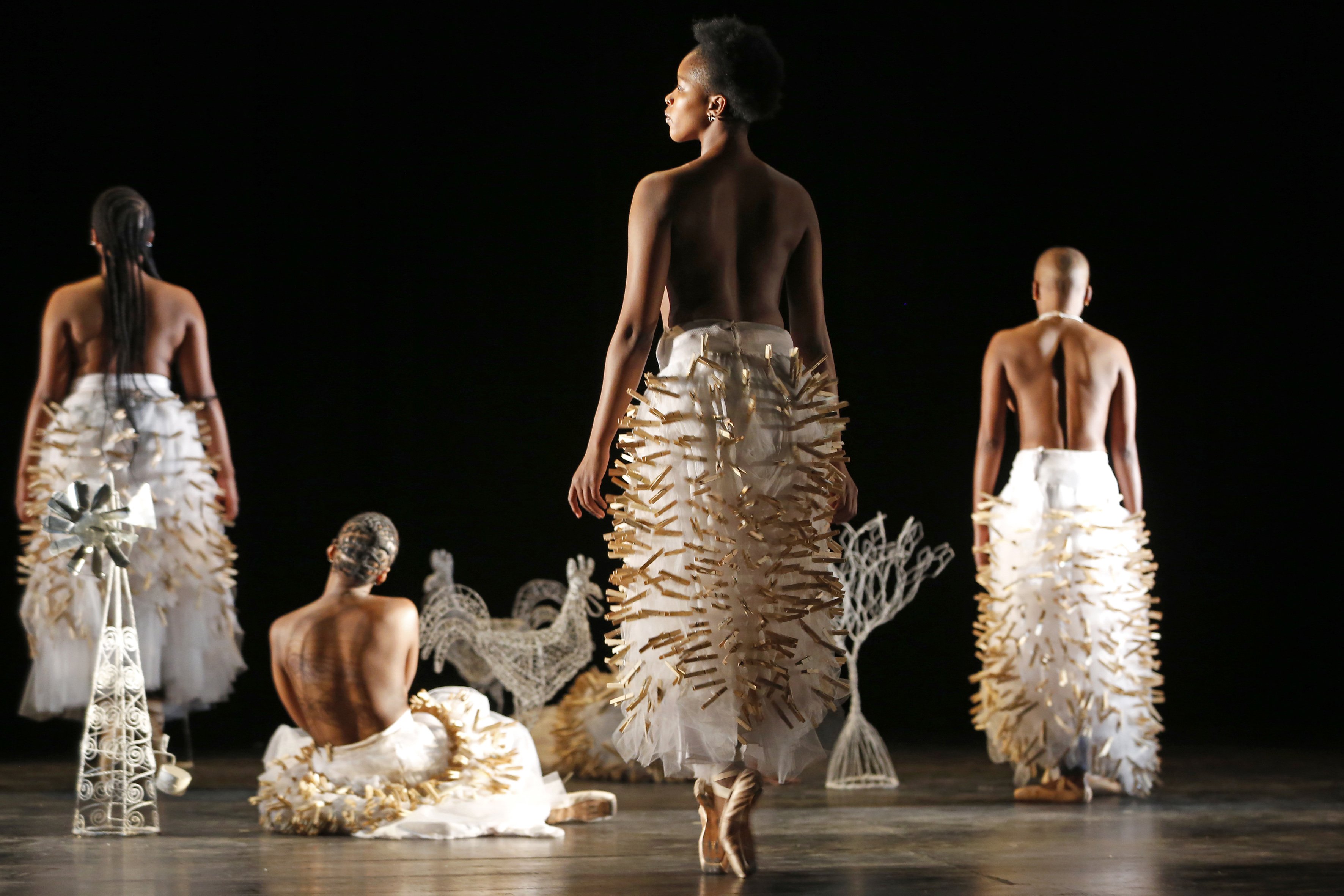 Quatre danseuses sur pointes, sur scène, de dos.