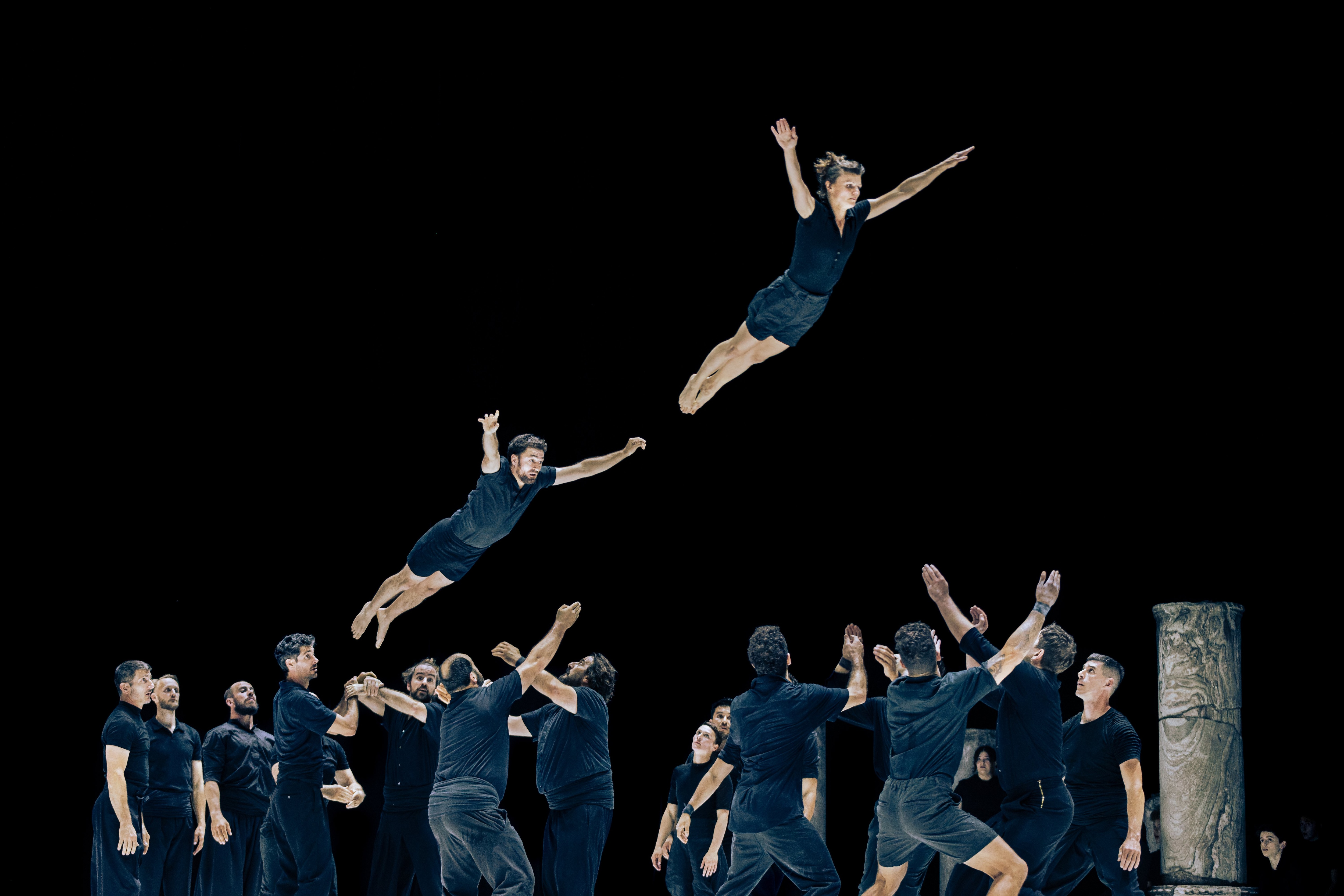 Deux danseurs sautant en l'air au dessus d'un groupe de danseurs