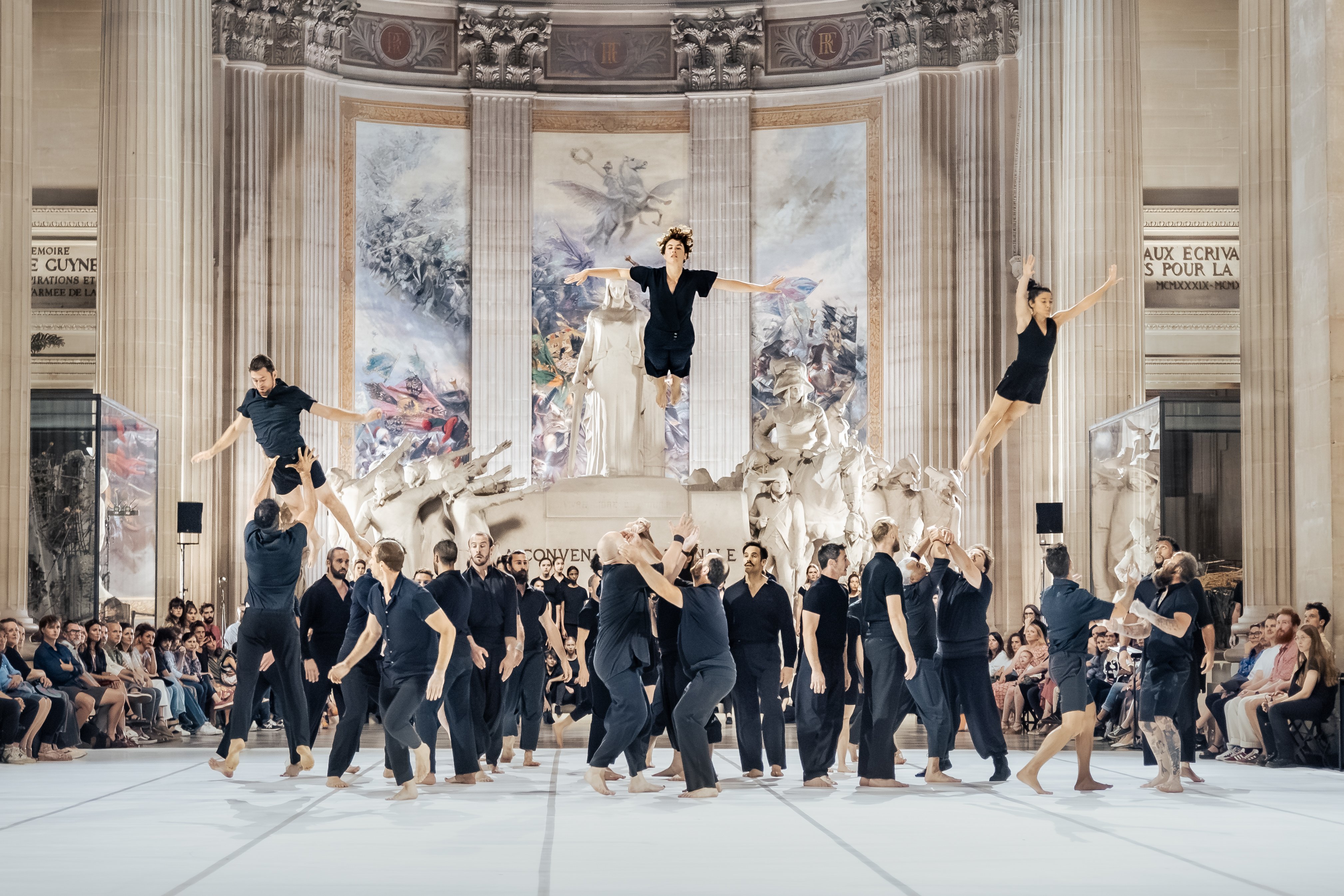 Danseurs en suspension en l'air au dessus d'un groupe de performeurs