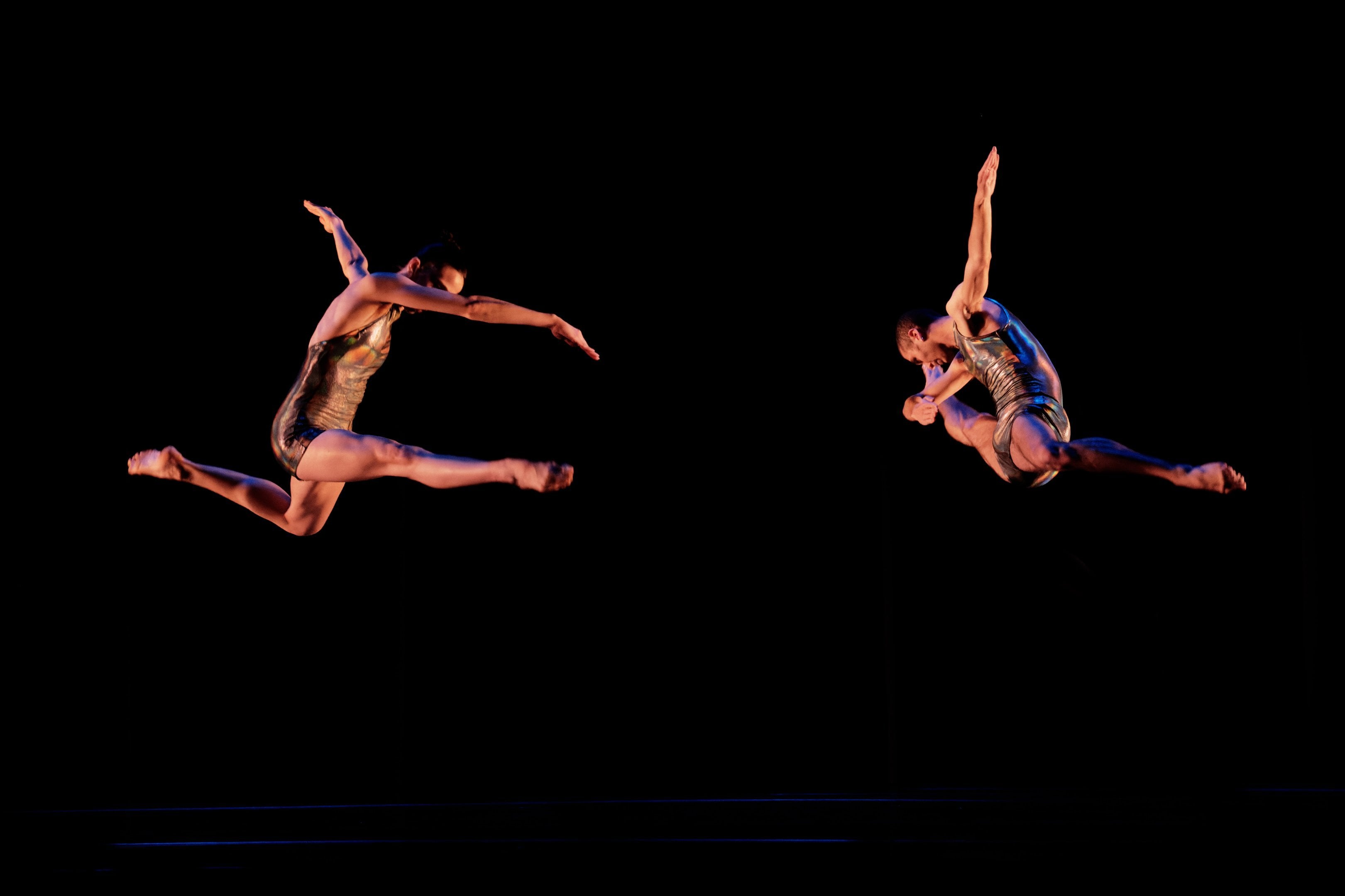 two dancers jumping on a black background