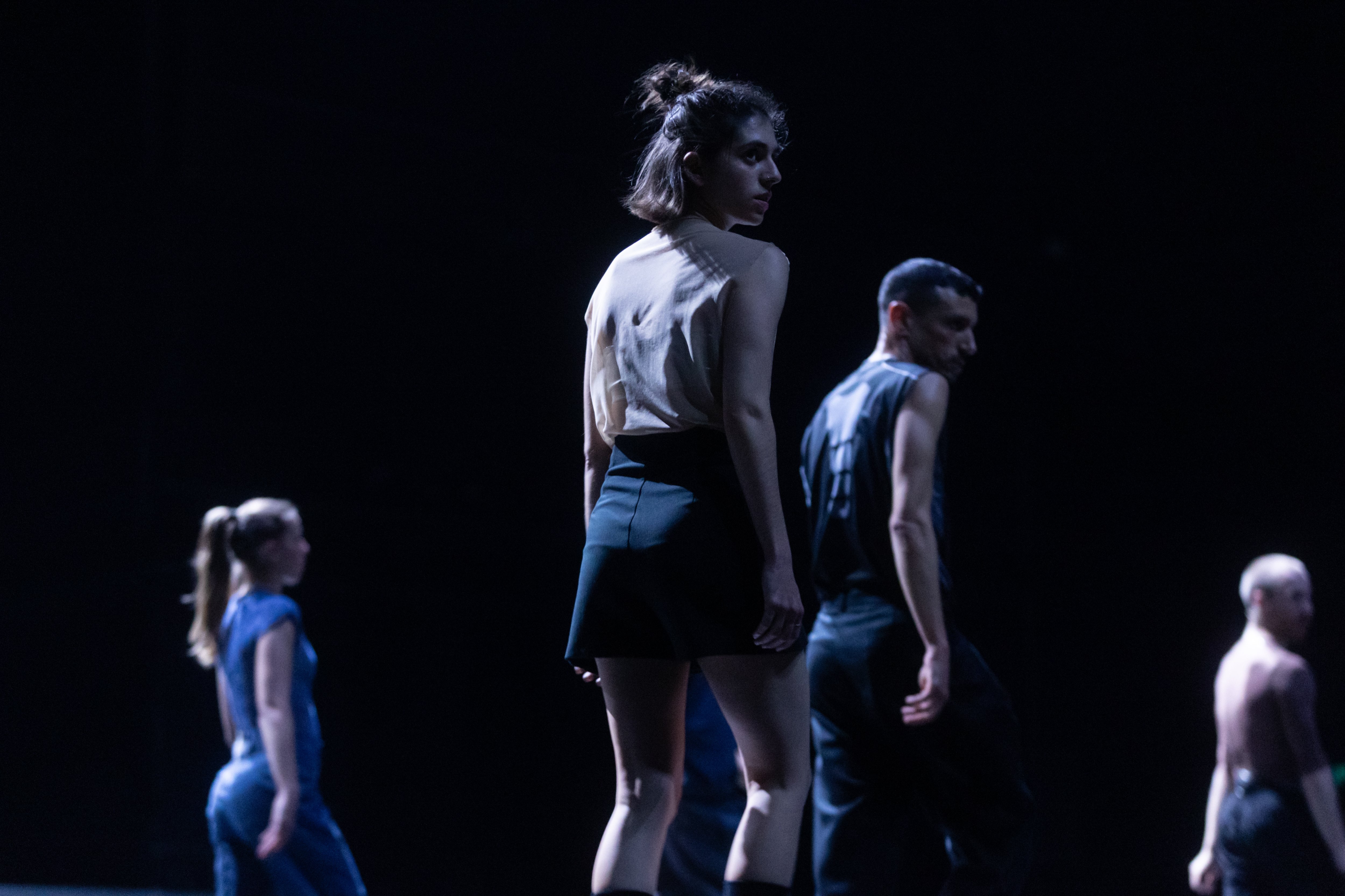  four people with their backs turned to the right on a black background