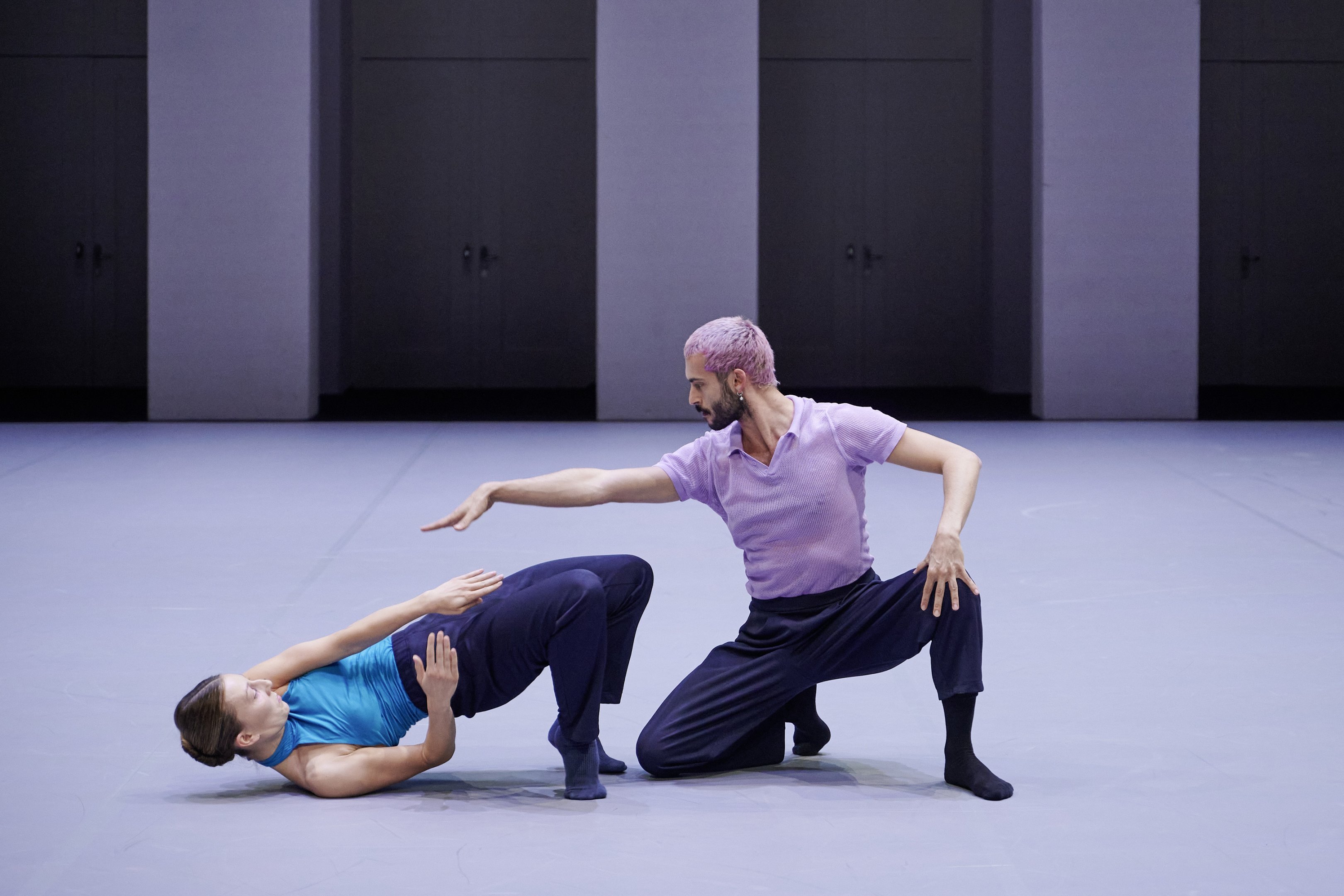 A female dancer on the ground and a male dancer kneeling