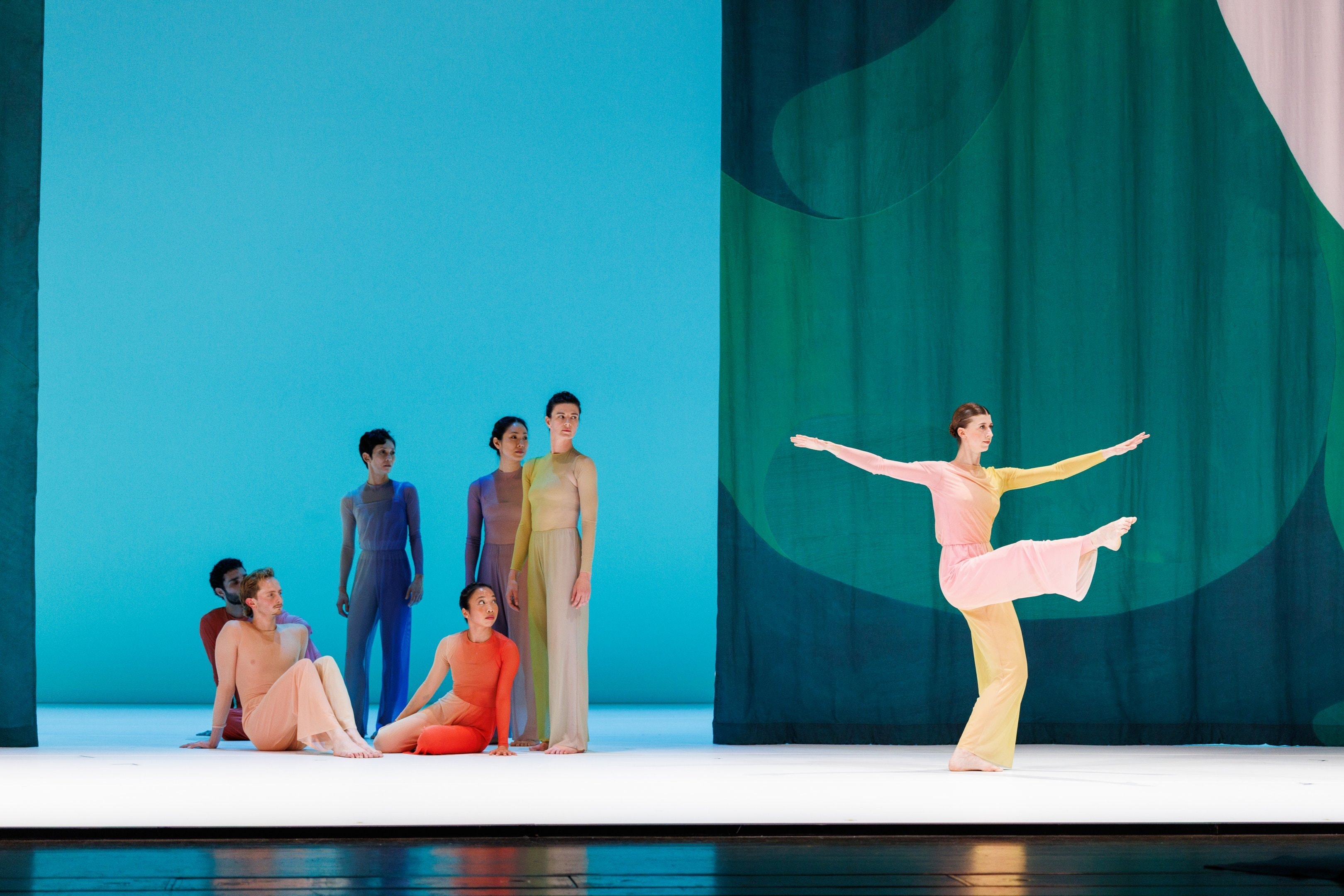A group of dancers on the left and a dancer in the light on the right.