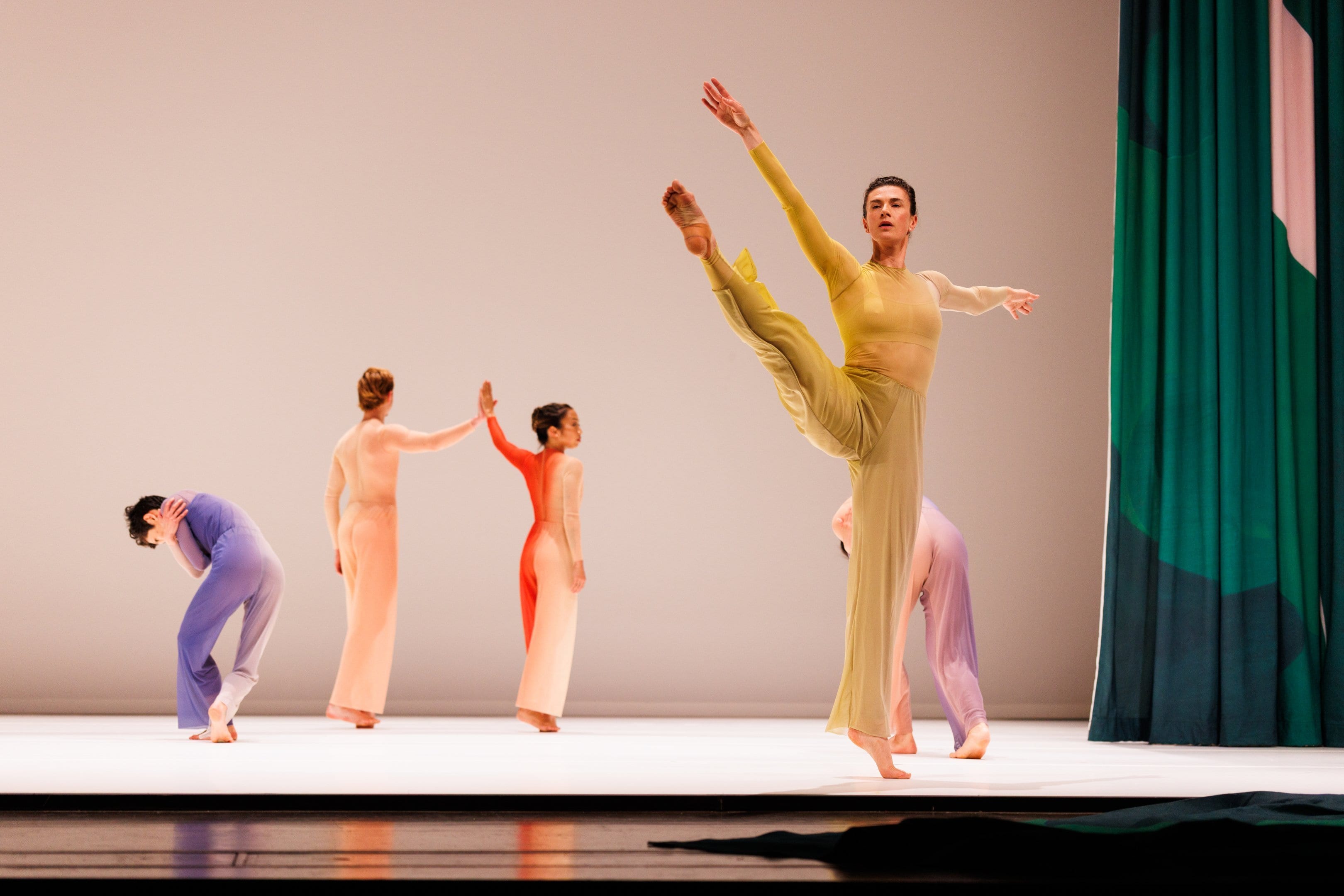 dancer in a yellow costume with three dancers in the background.