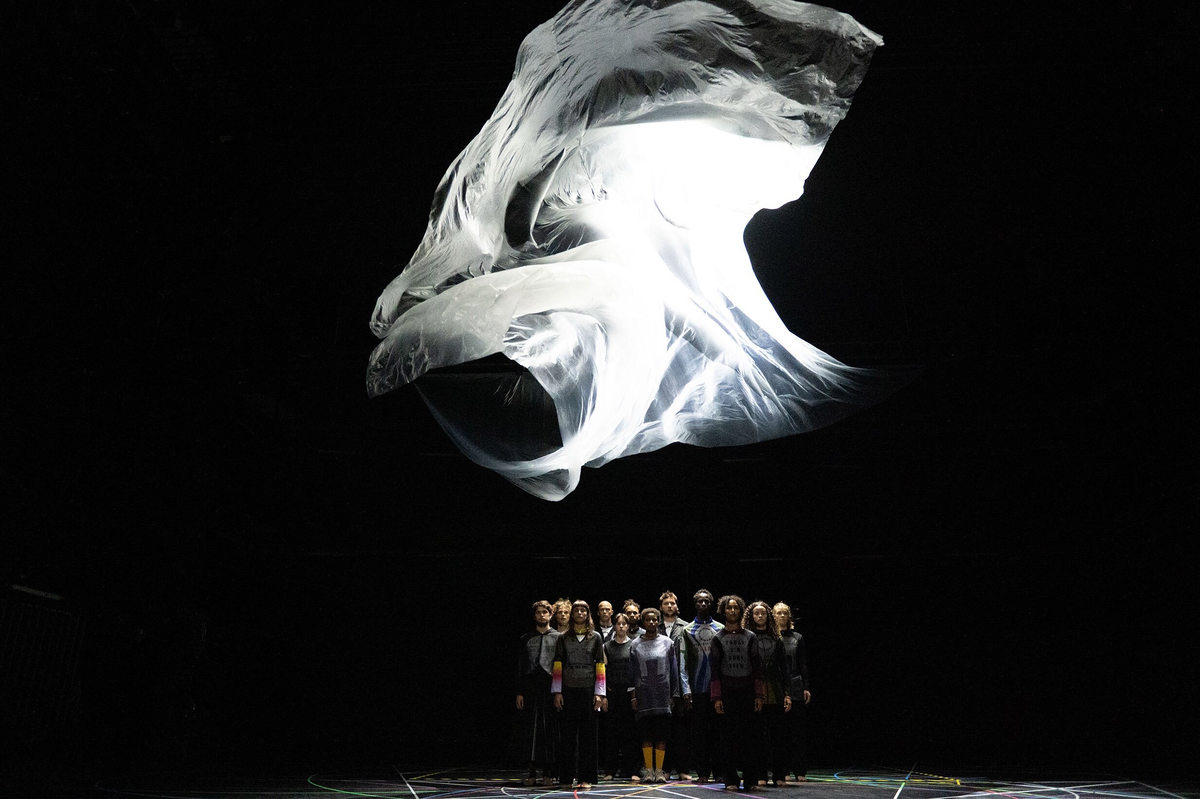 groupe de danseurs debout, avec un grand tissu blanc au dessus d'eux