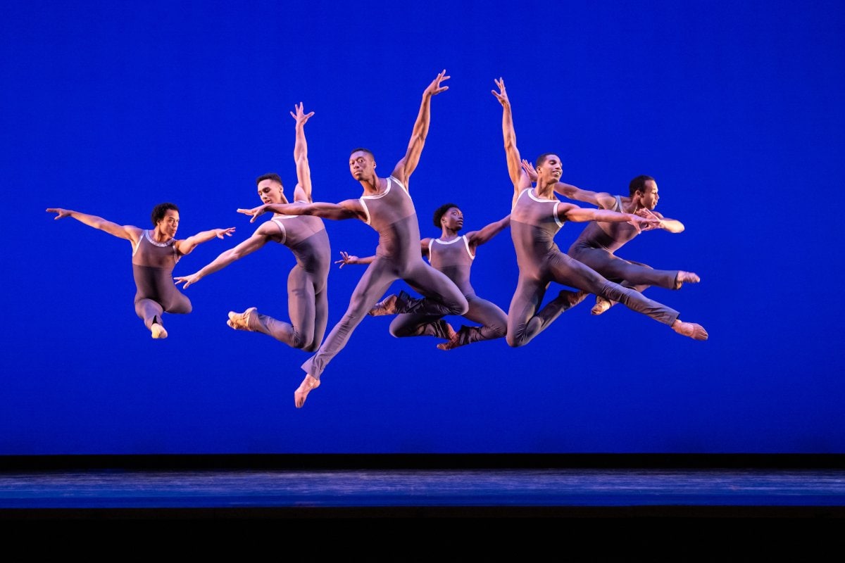 group of 6 dancers performing in front of a blue background 