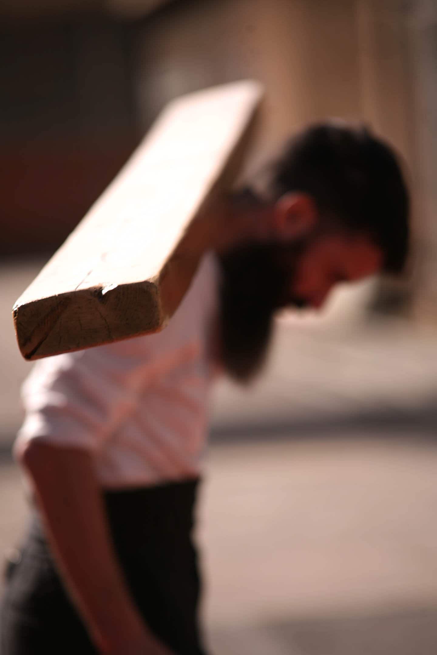 a man carrying a wooden plank on his shoulder
