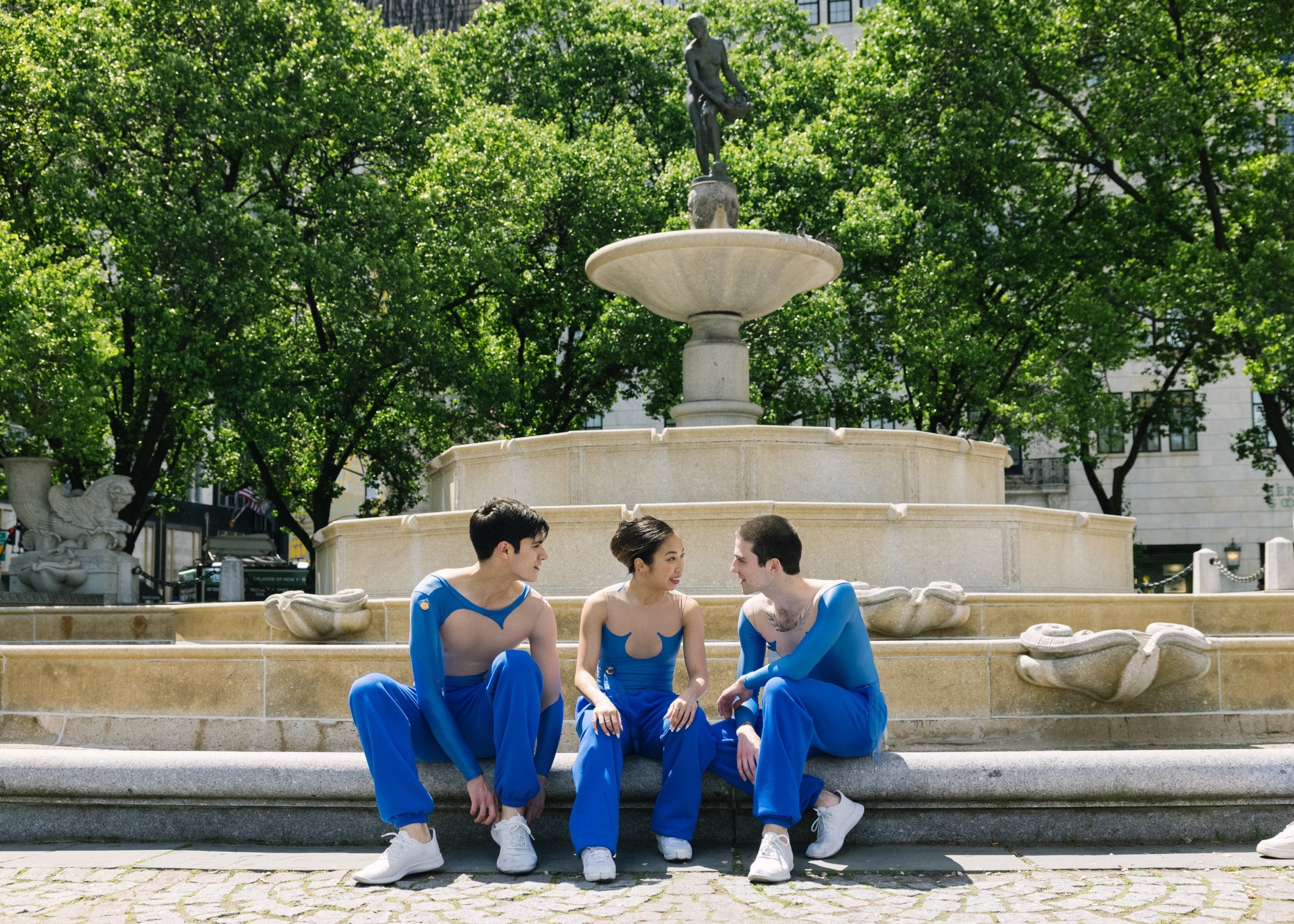 3 dancers sitting in front of the Pulitzer Fountain