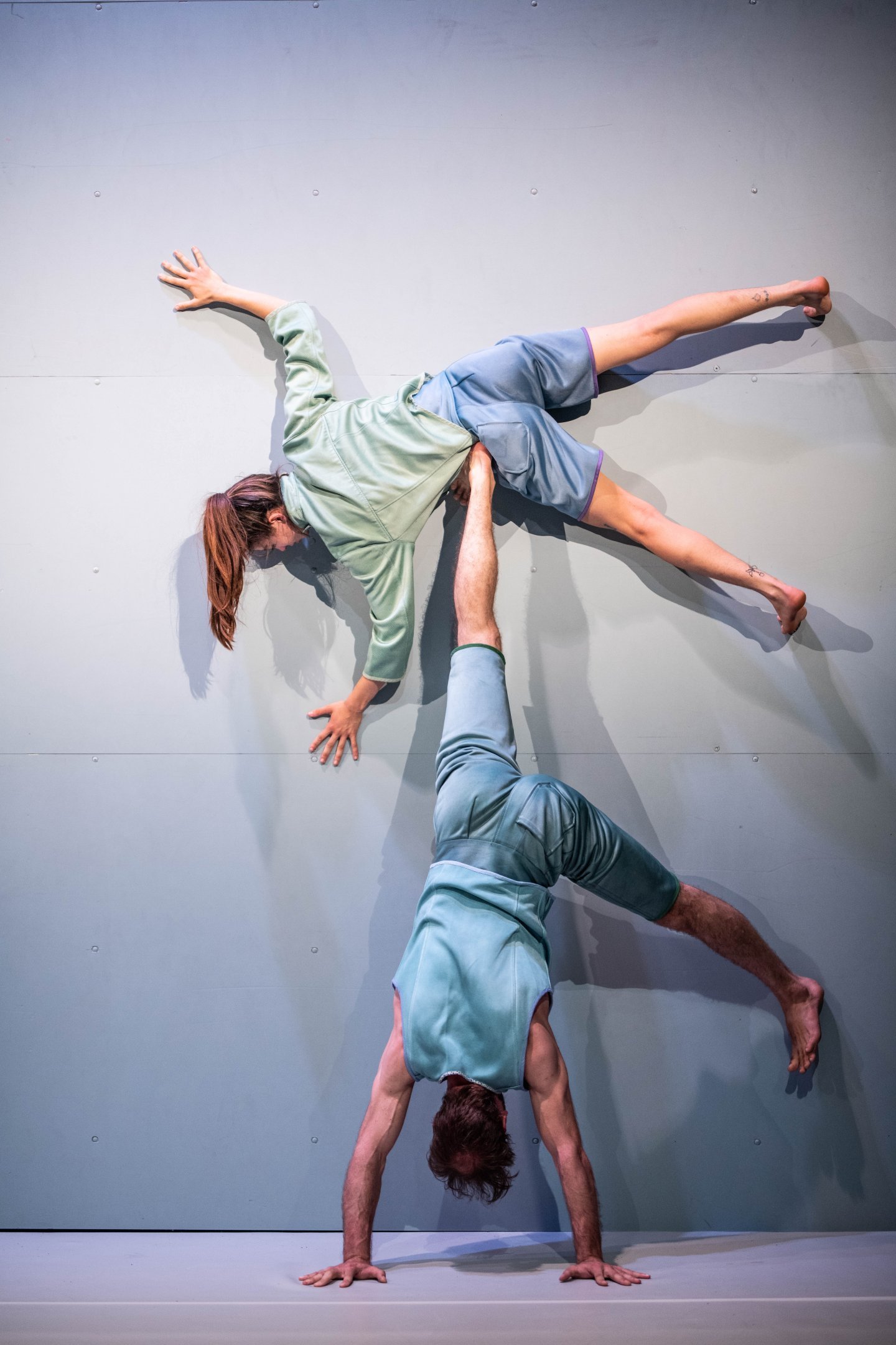 Duo of dancers performing a figure against a wall