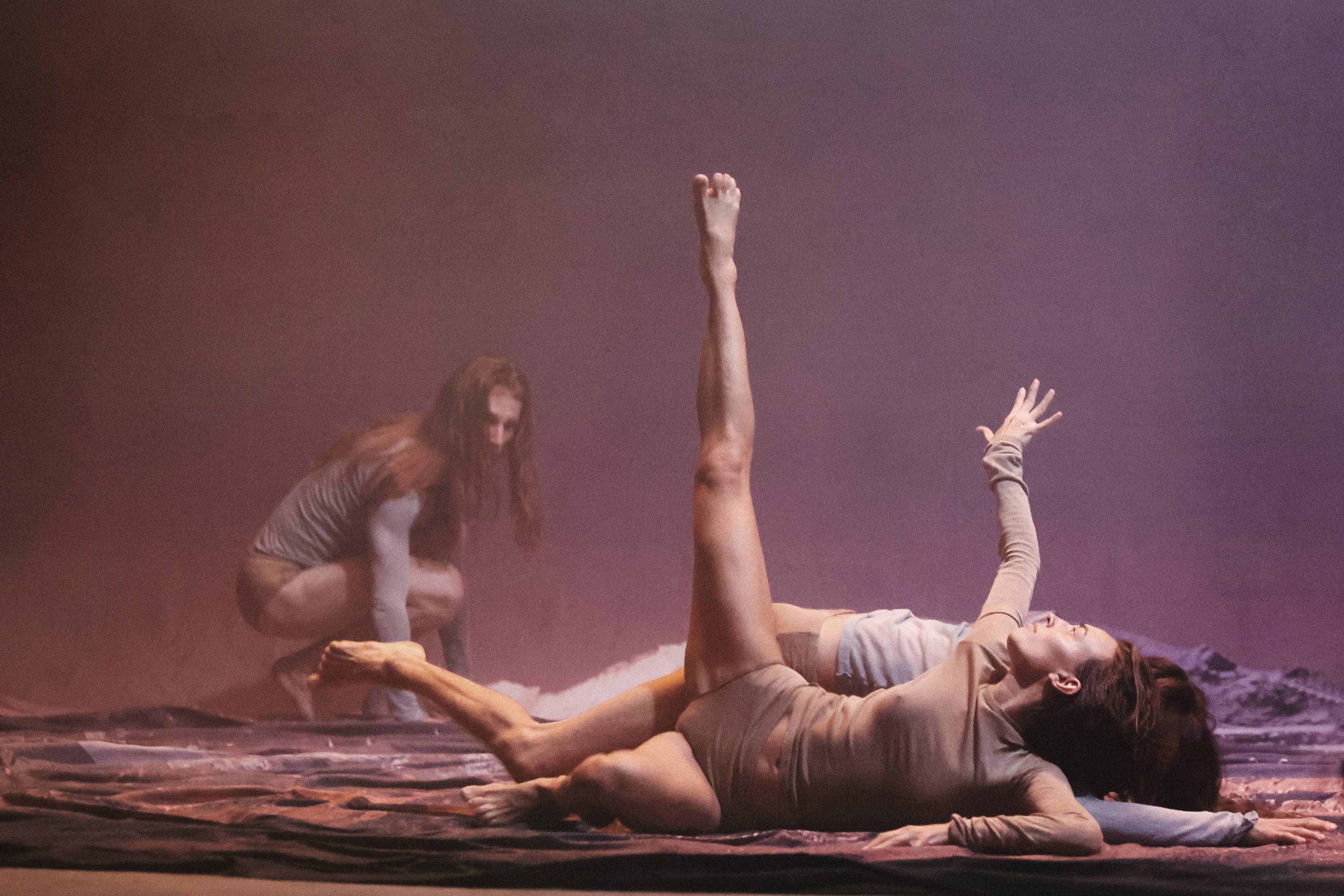 Photo d'une représentation du spectacle Mont Ventoux Kor'sia montrant une danseuse allongée au premier plan avec deux autres danseurs en arrière-plan