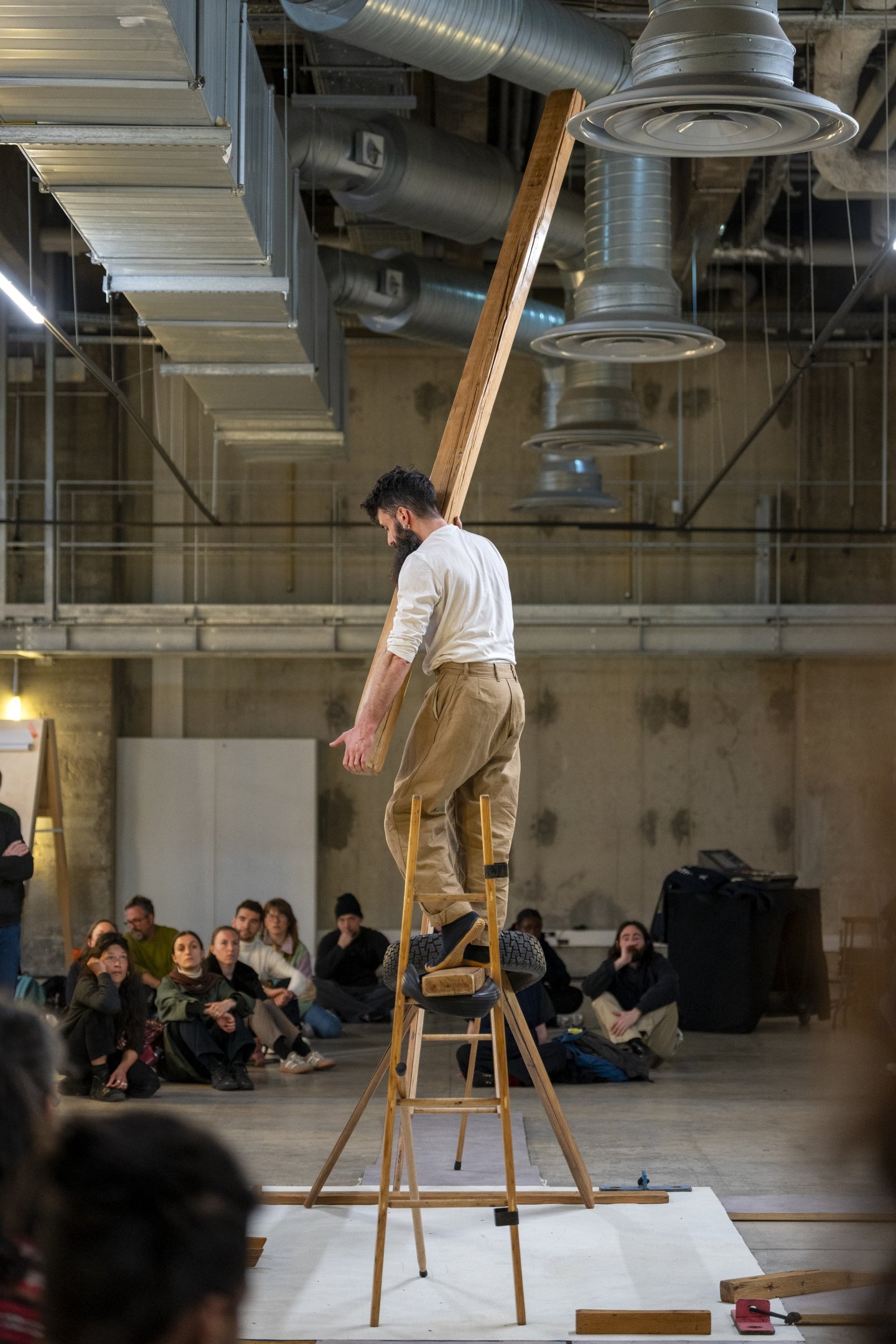 un homme sur un escabeau en bois tenant une poutre en bois