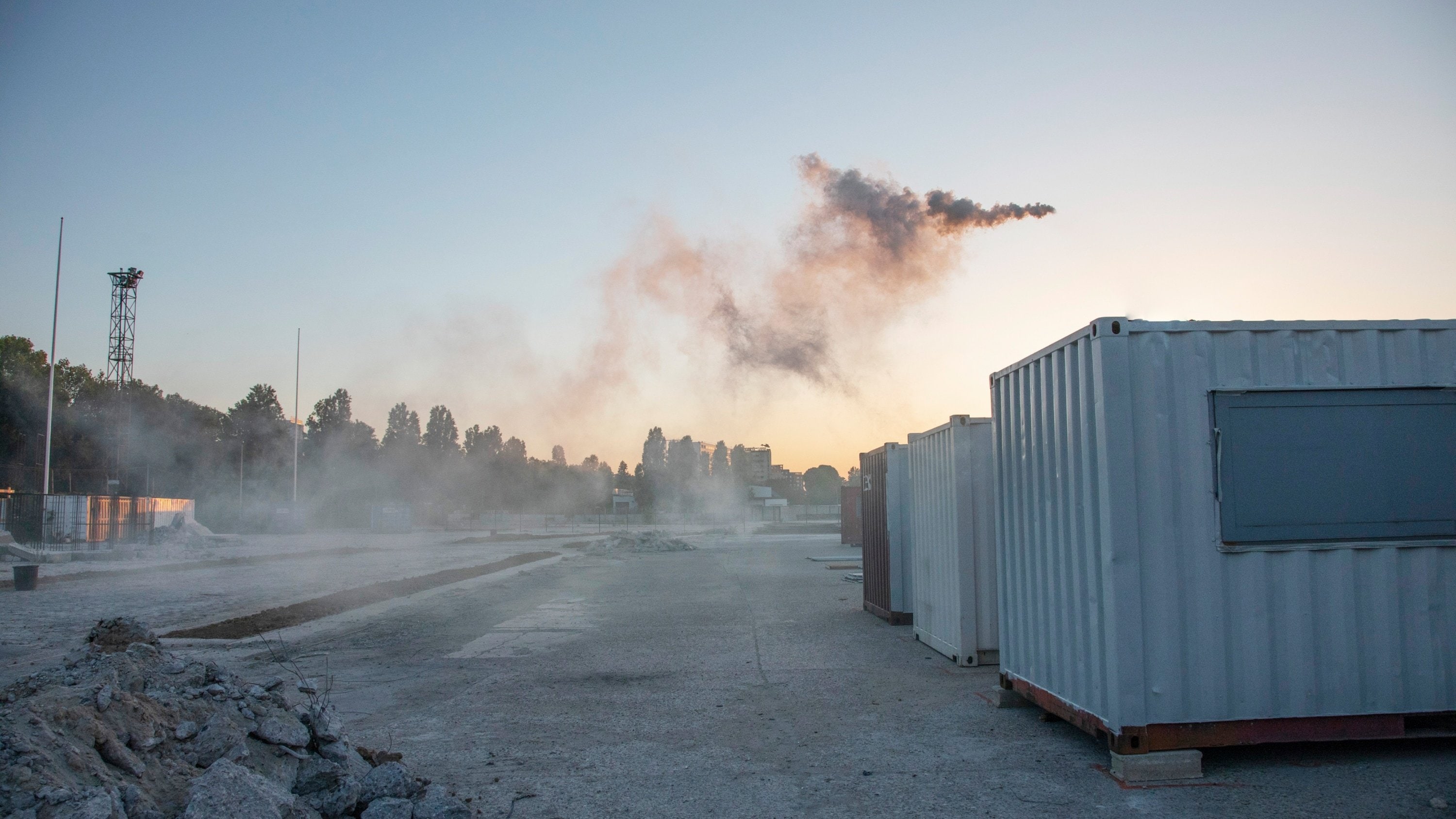 Conteneurs sur sol en béton, gravas et fumée