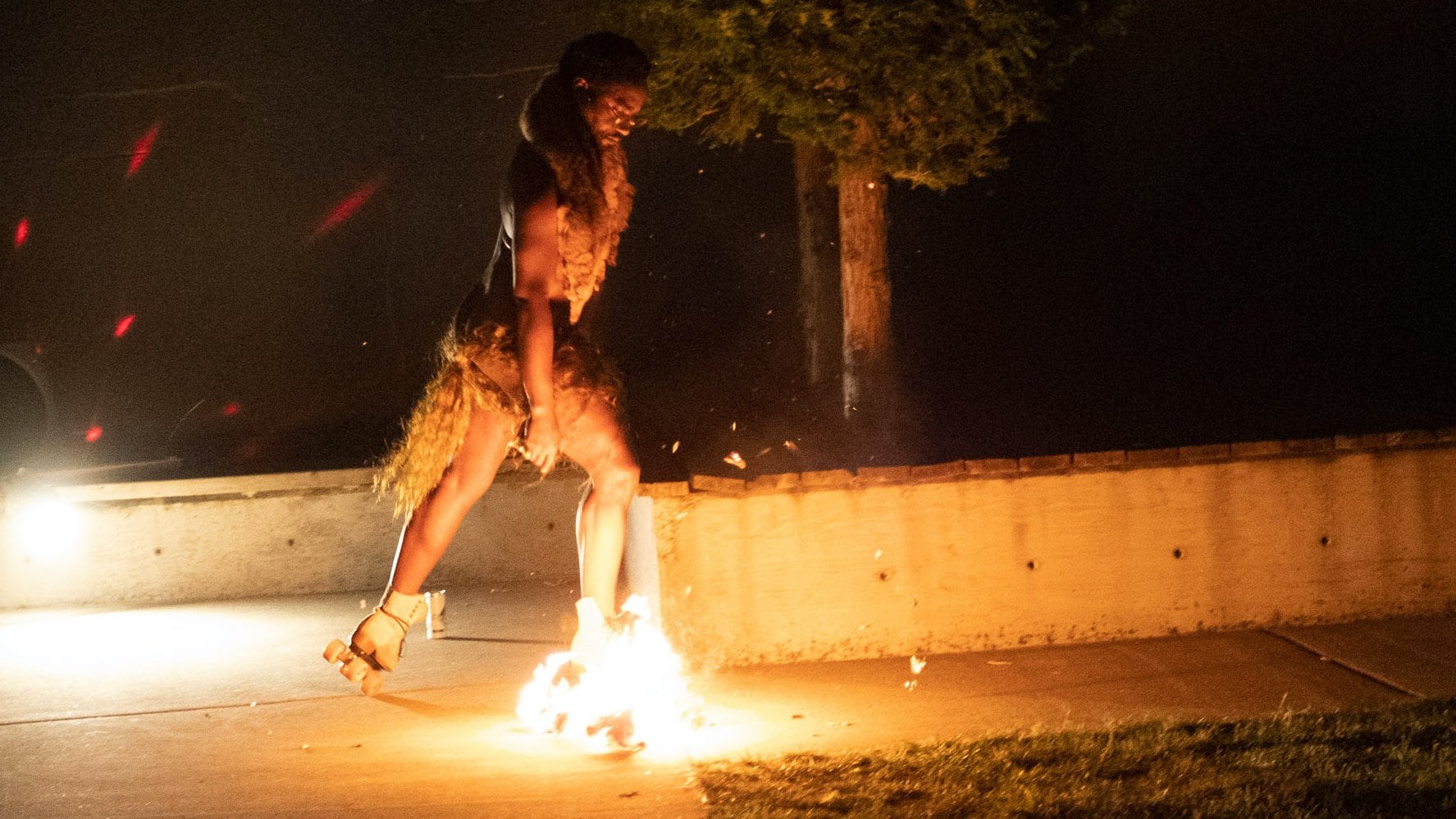 a dancer rollerskating during nighttime with one boot on fire