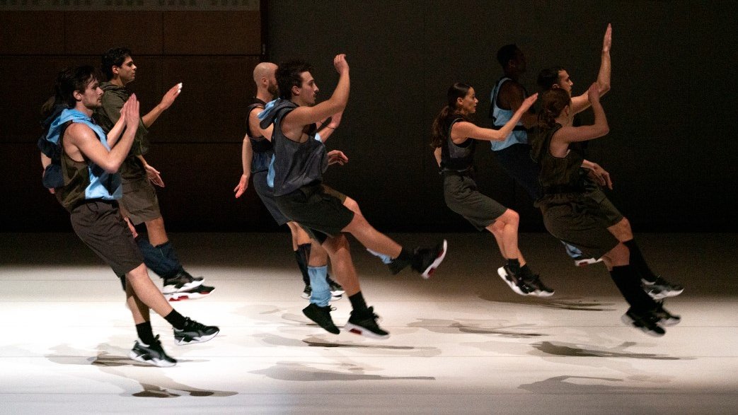 Dancers on stage all jumping at the same time with lifted arms