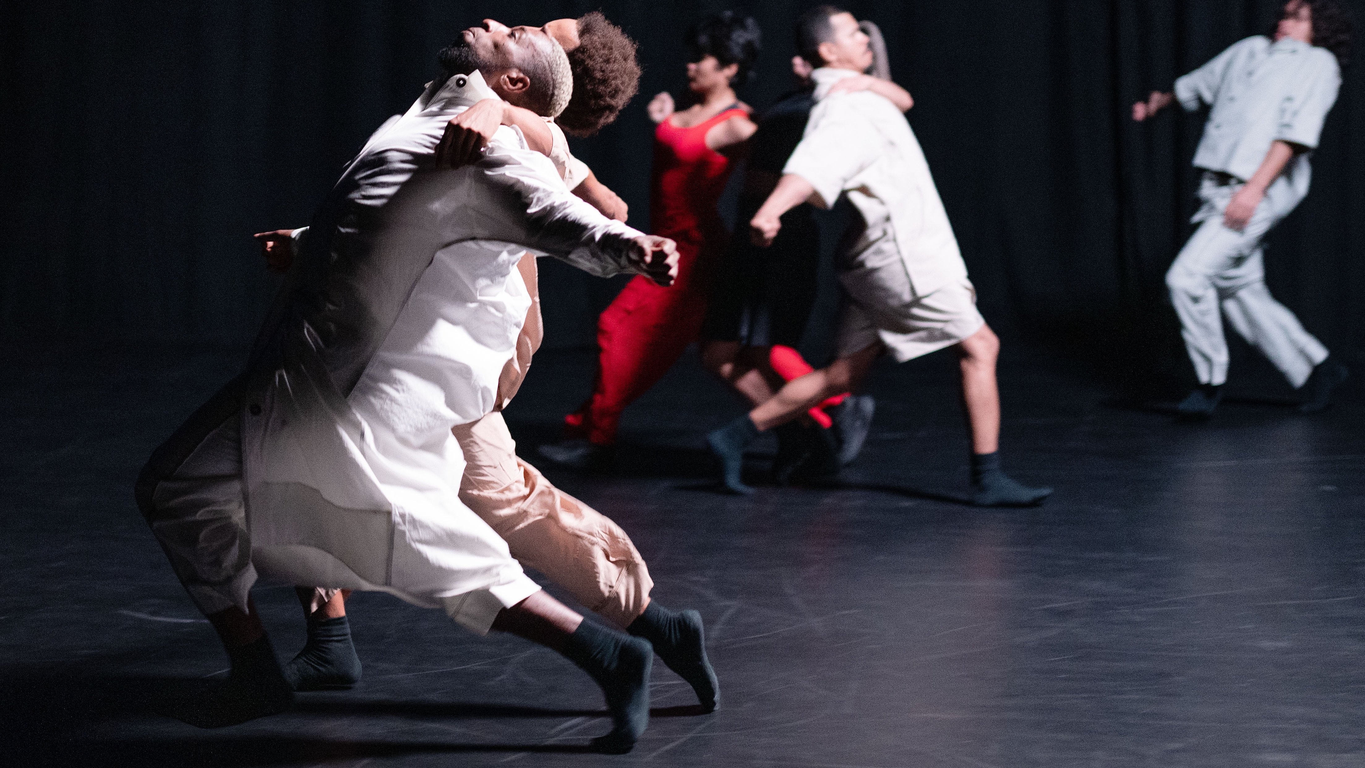 Dancers dressed in white, leaning back