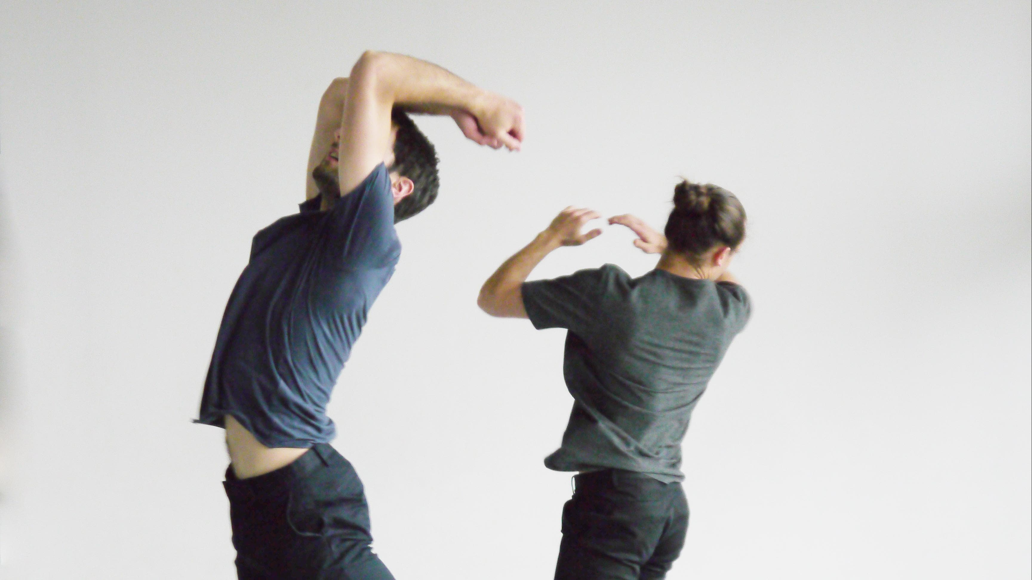 Deux hommes sautant dans une salle grise