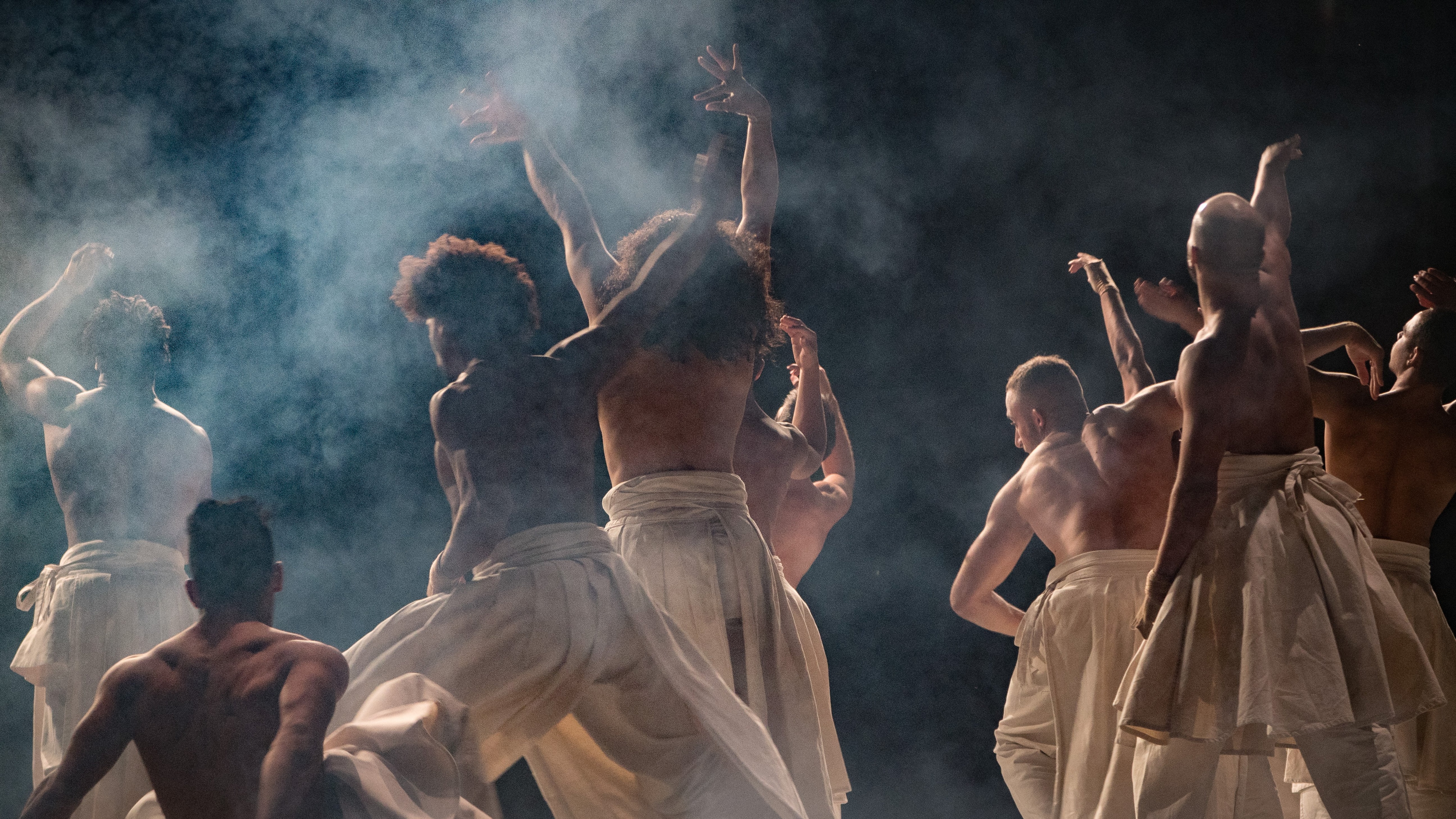 Danseurs en sarouels blancs sur une scène sombre 