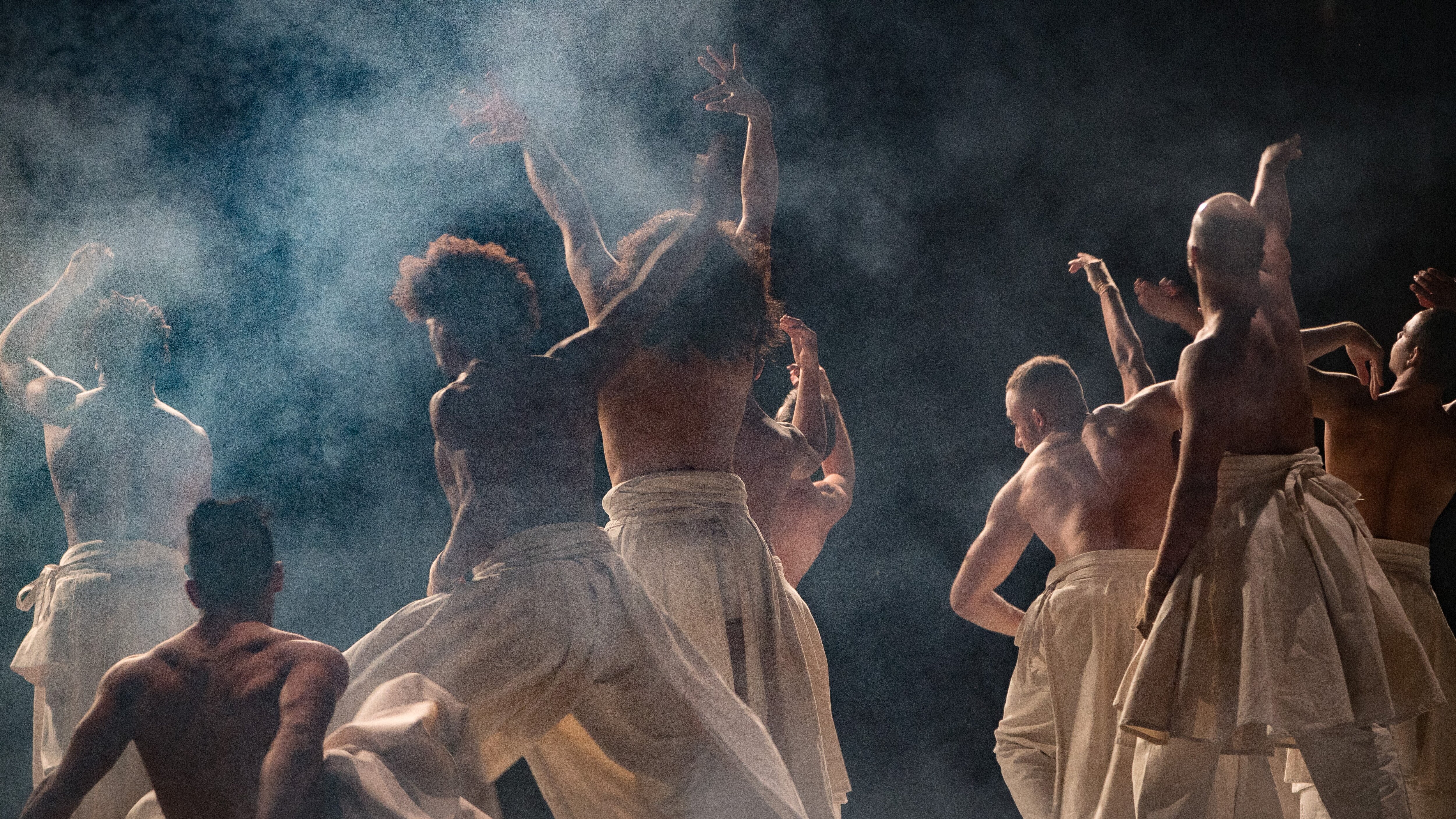 Dancers wearing sirwal pants on a dark stage