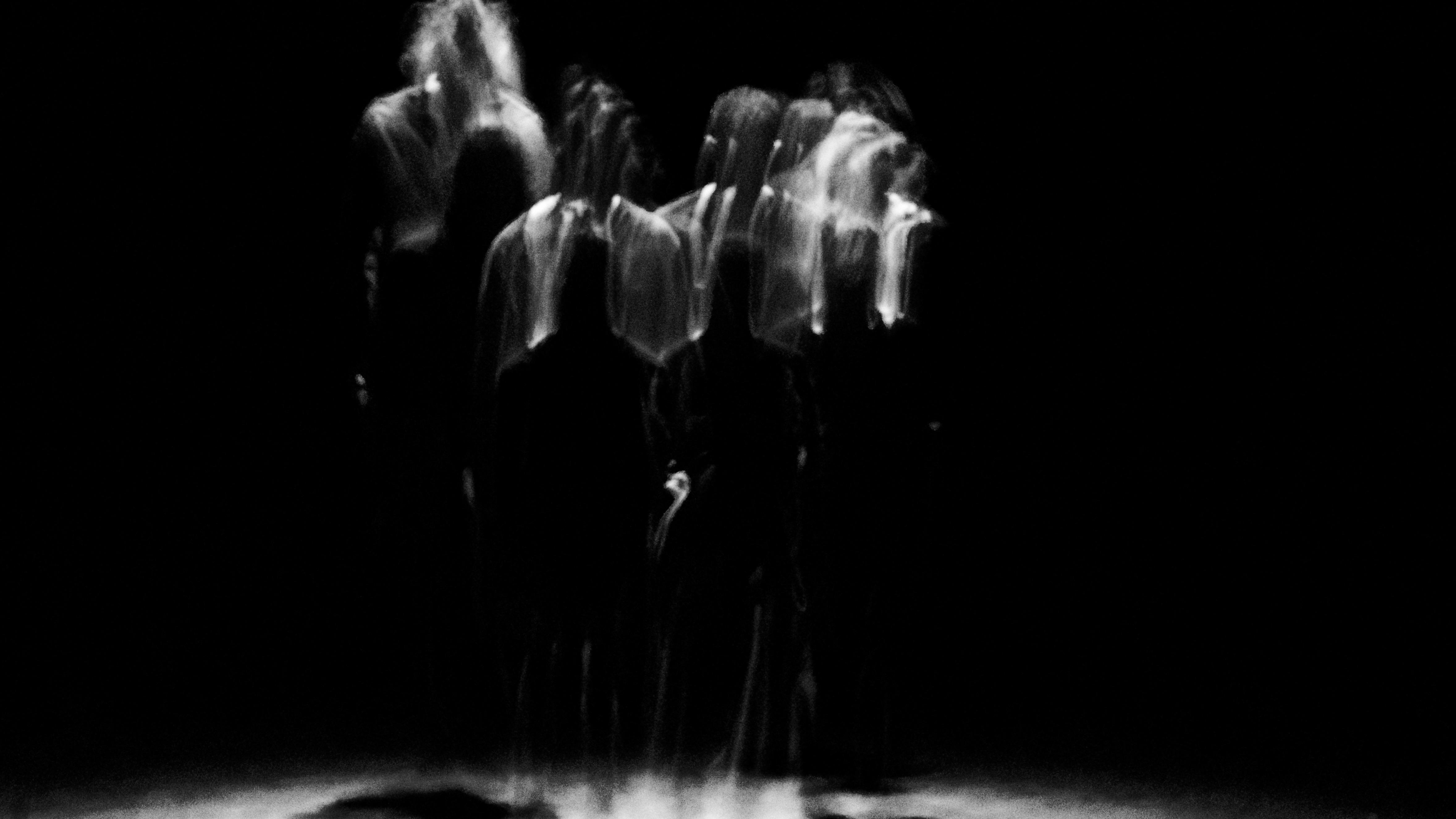 Blurry silhouettes dancing in the dark, illuminated by a ray of light