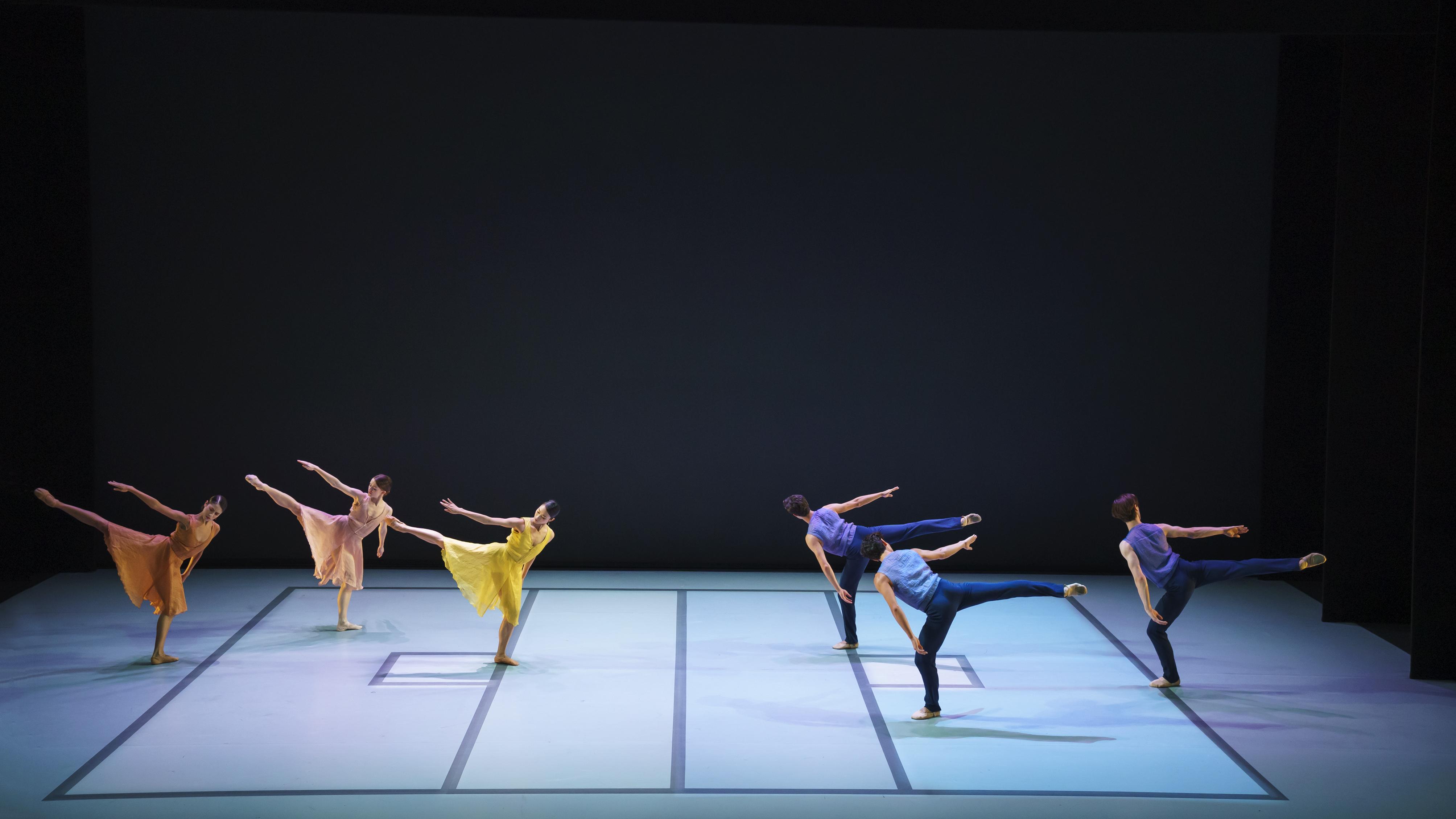 Danseurs vêtus de couleurs vives, avec le bras droit et la jambe droite levés.