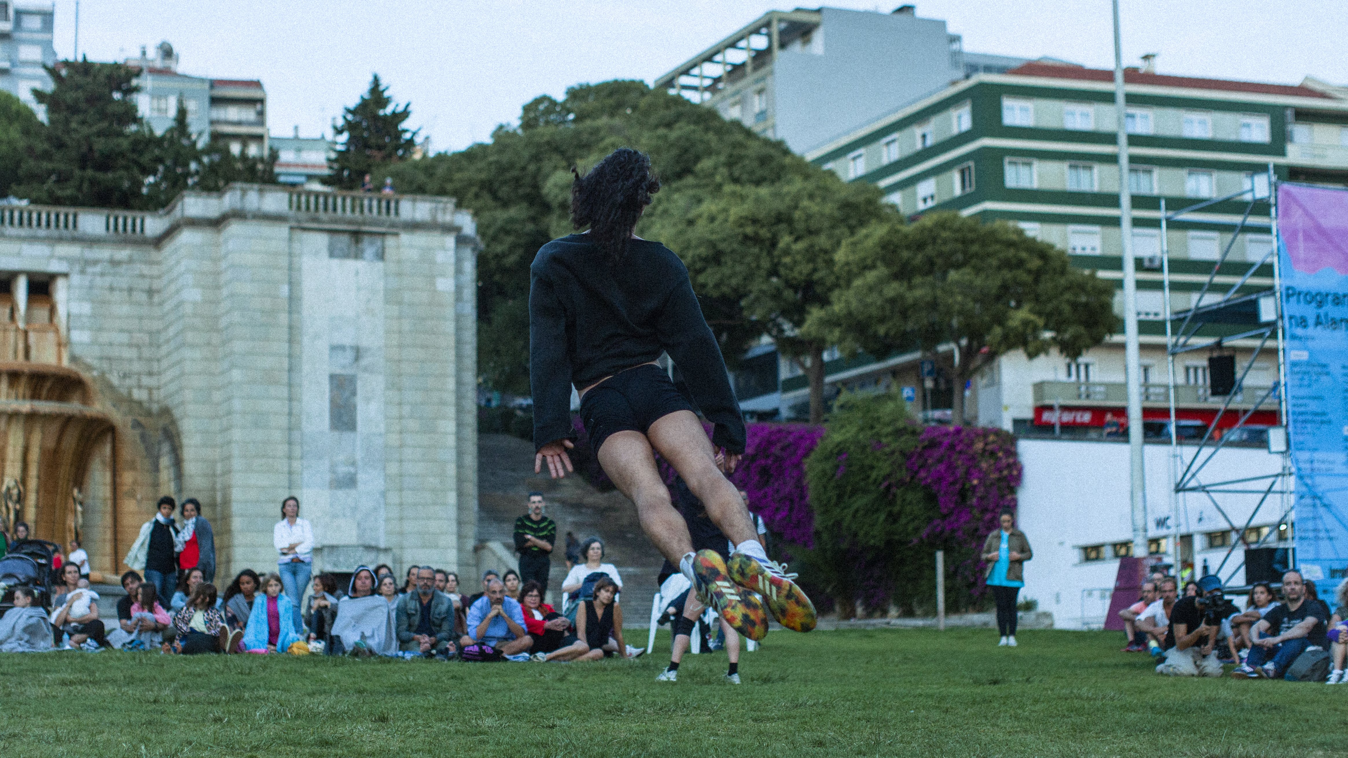 a dancer jumping in a garden, facing away