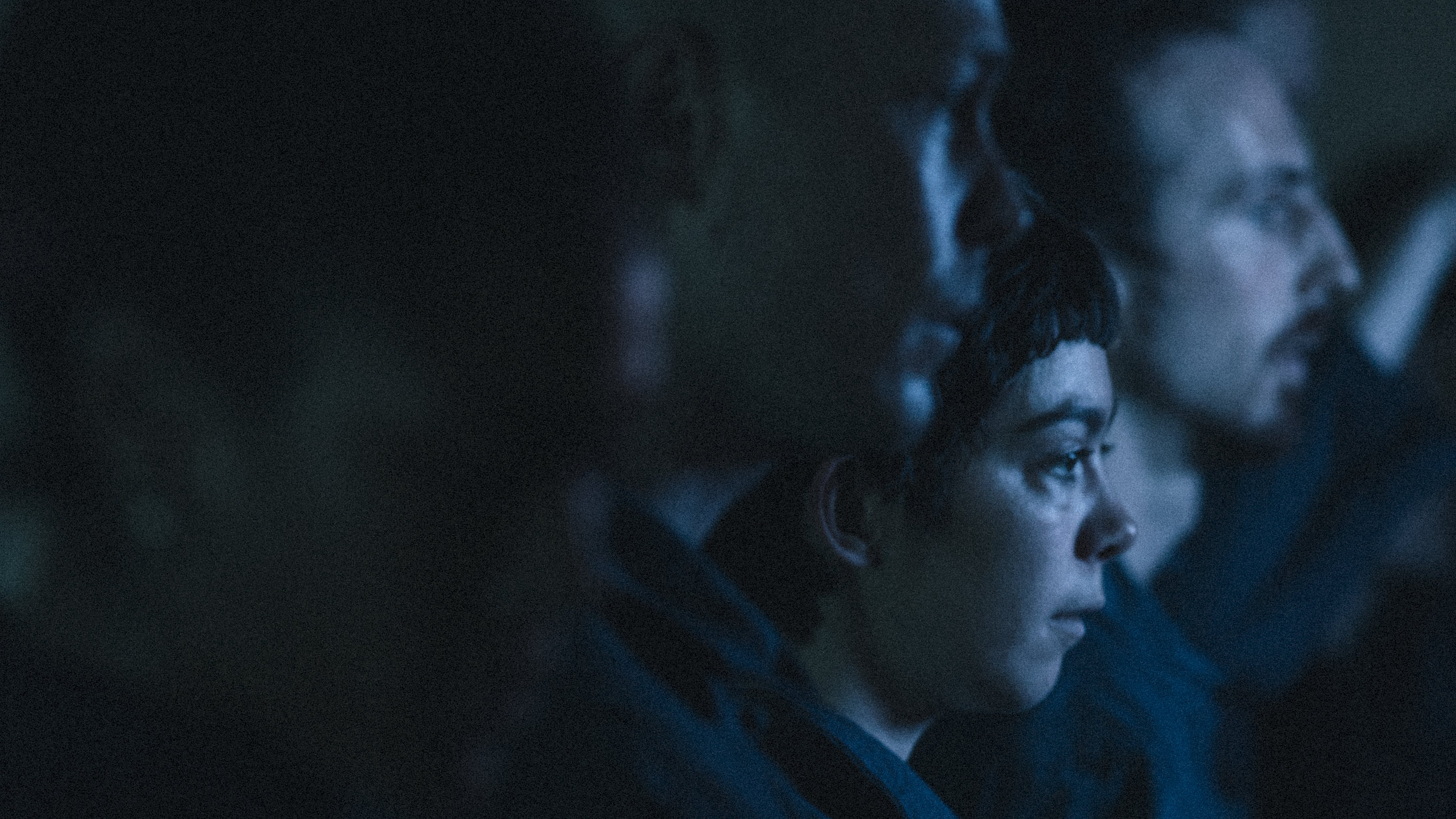 dancers seen in profile, in a dark room with a navy blue light