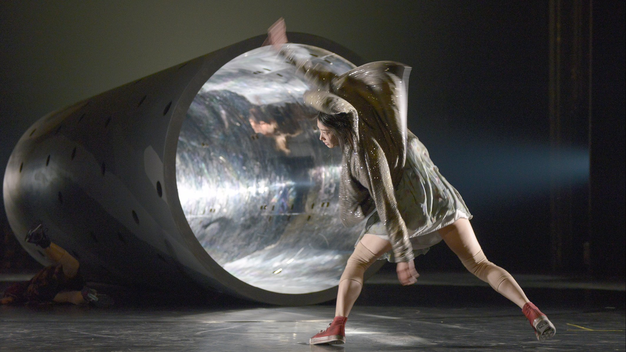 Woman dancing in front of a tunnel illuminated by a ray of light