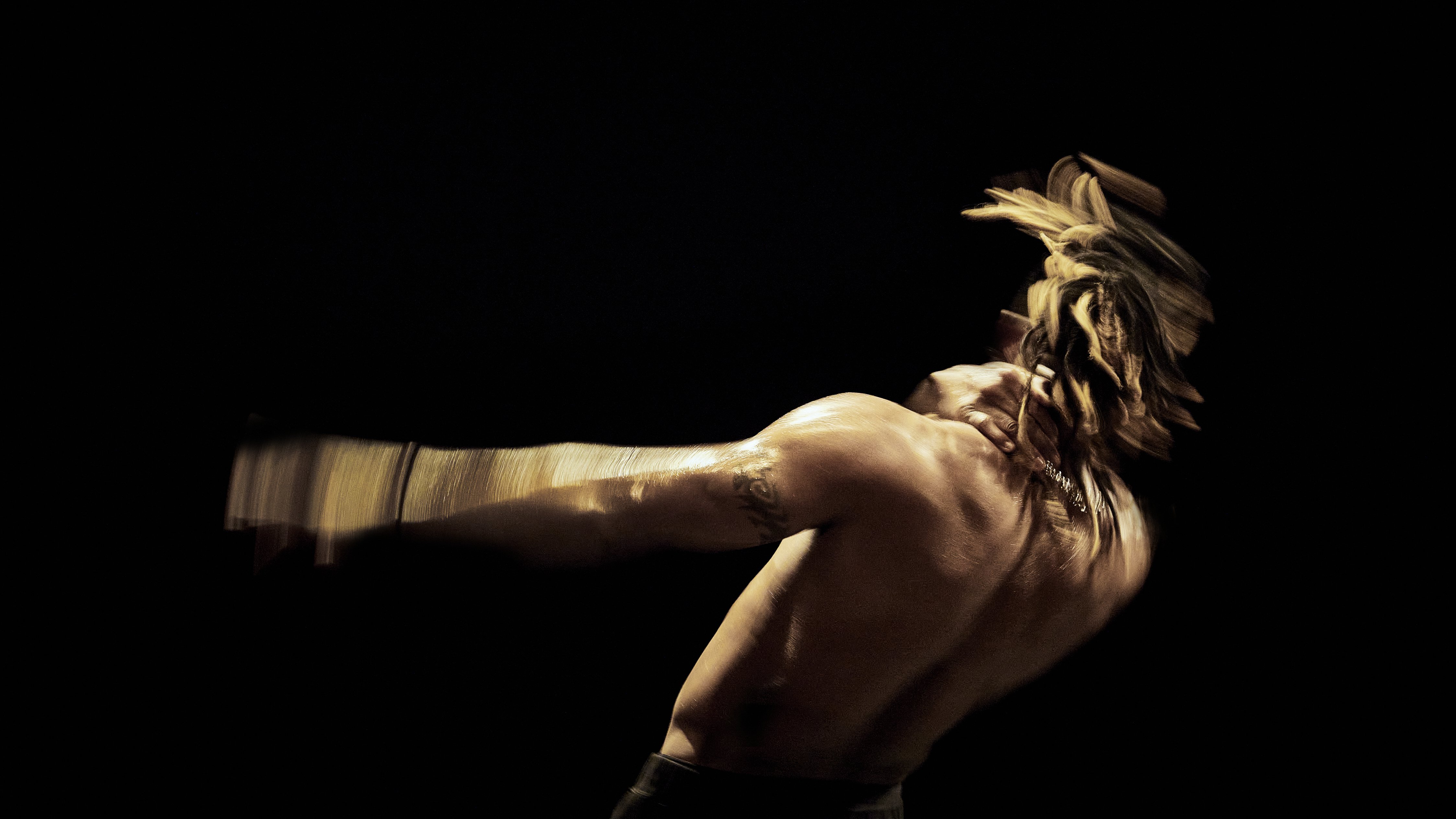 Michel « Meech » Onomo from the back, shirtless and moving in a black background