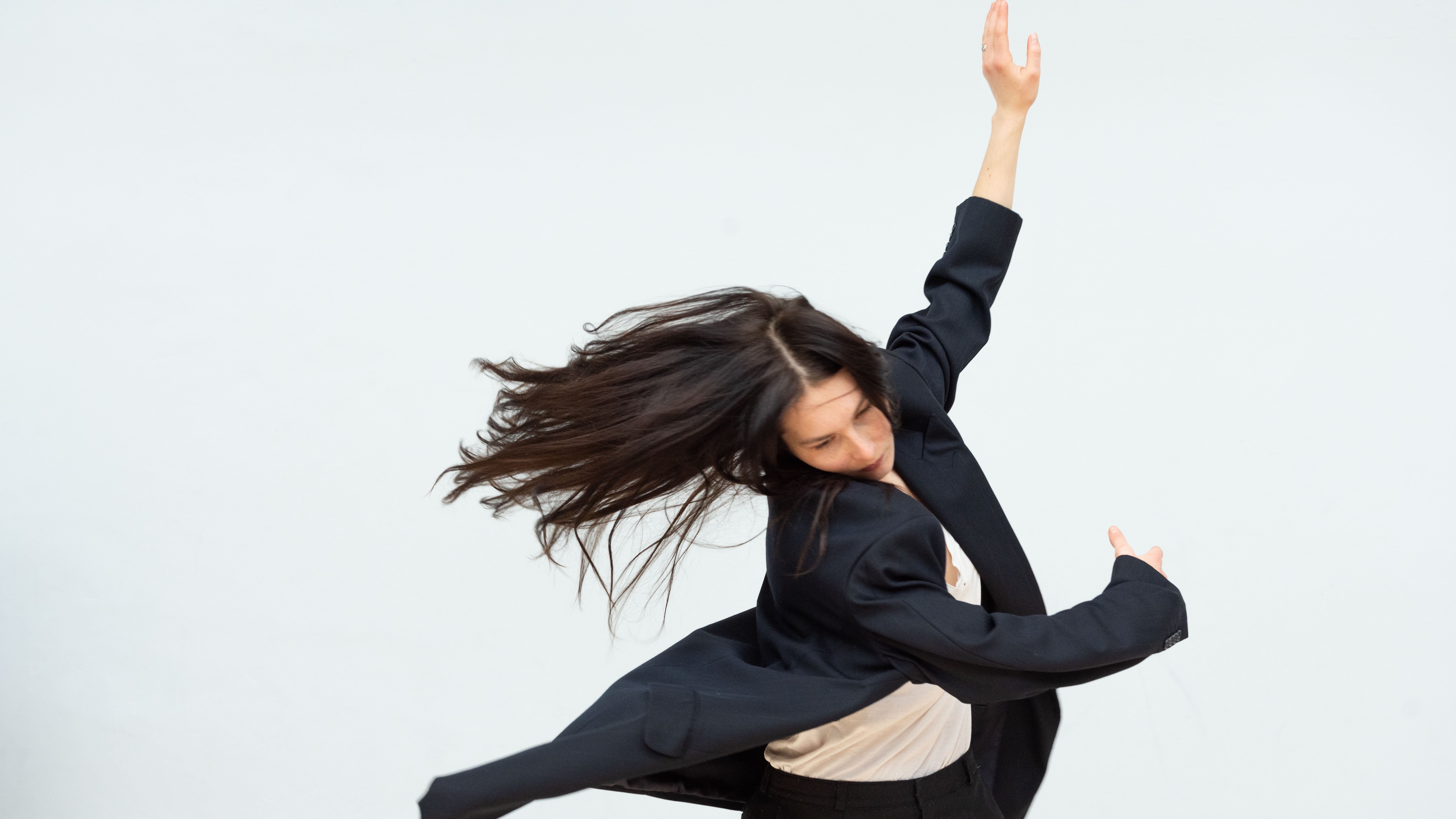 A dancer performing Anne Teresa De Keersmaeker’s Sand/Encore 1Été, her arms in movement to her side