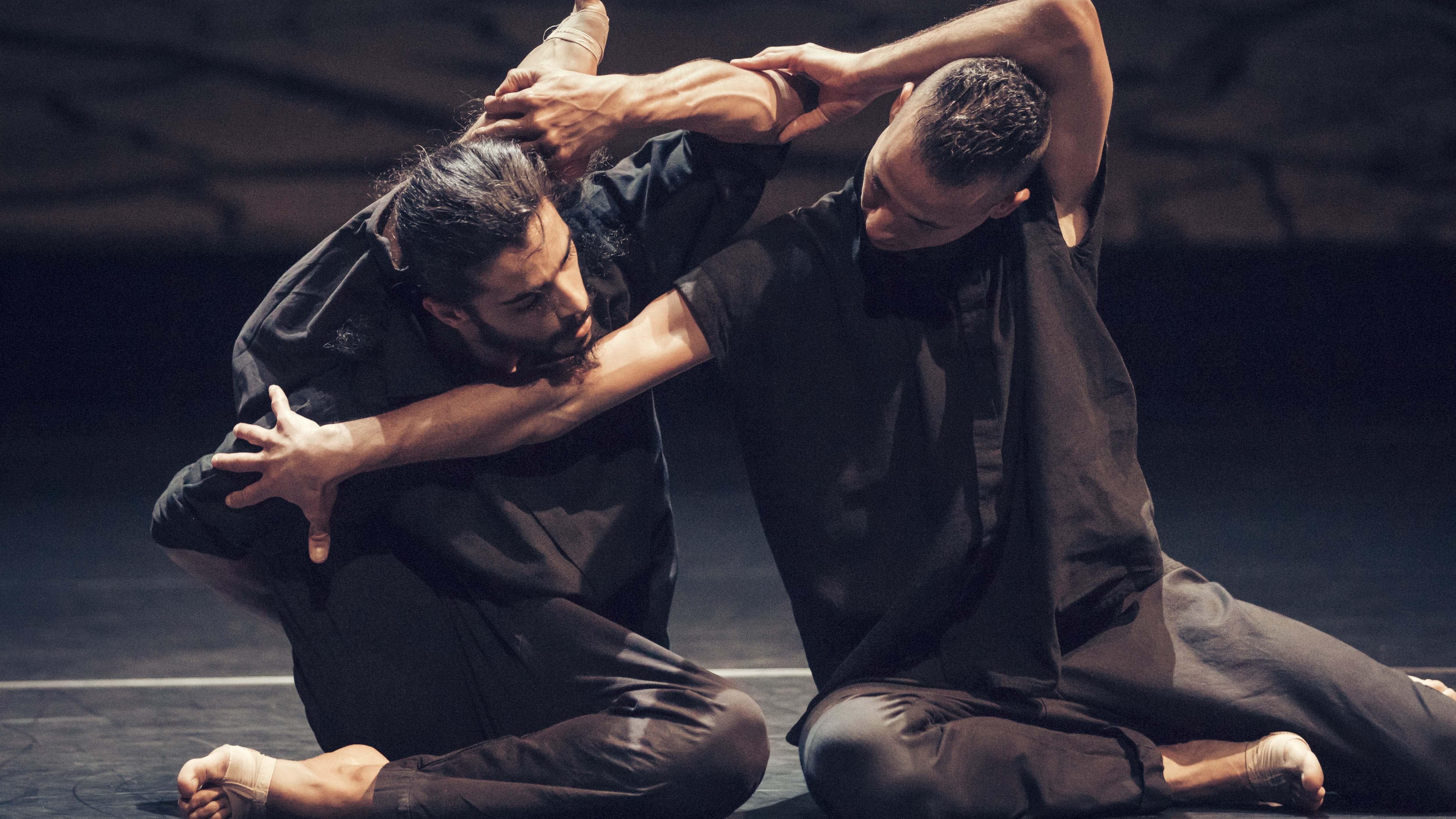 Deux danseurs vêtus de noir assis sur le sol