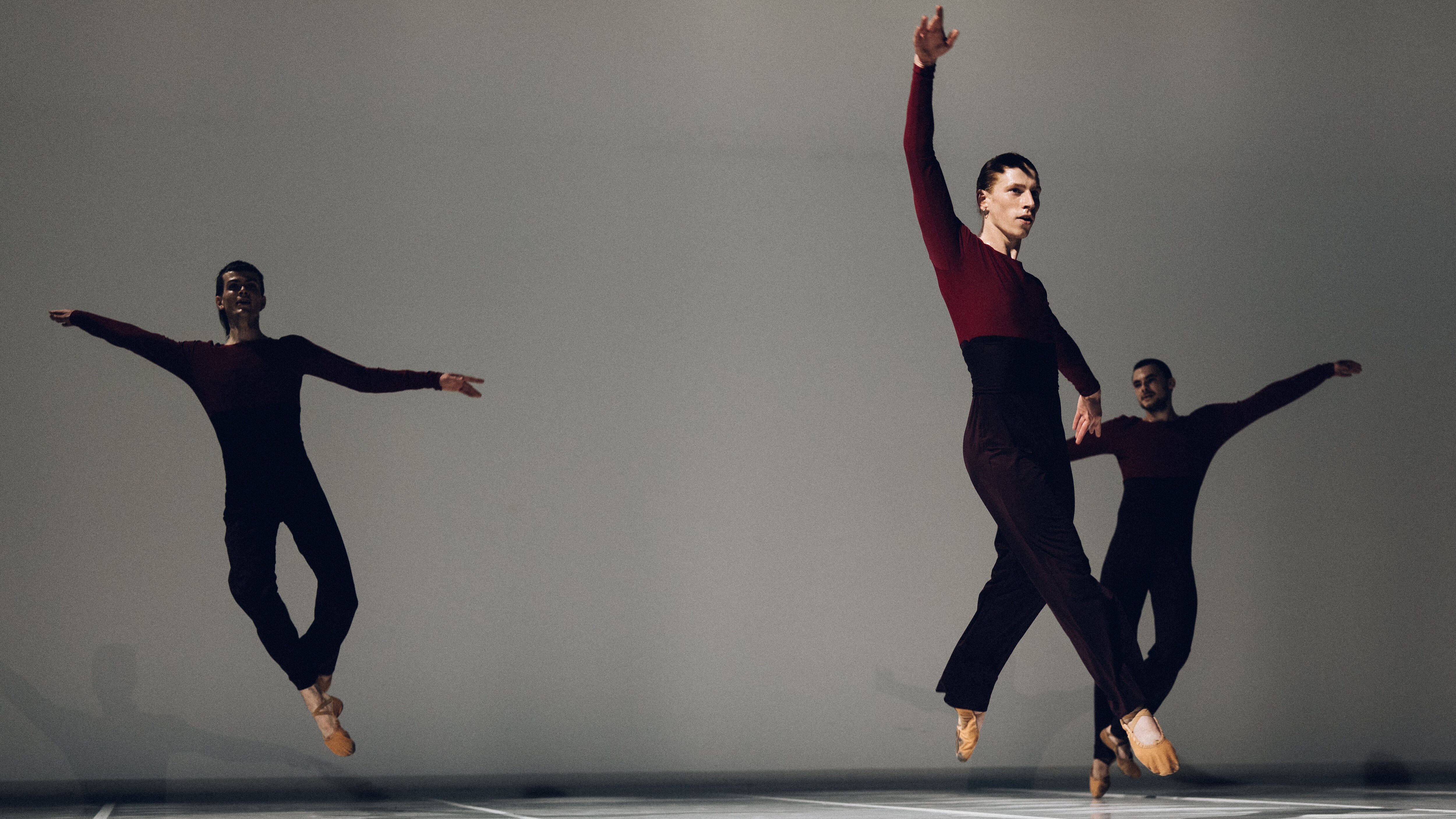 Sept danseurs en mouvement devant un mur orange