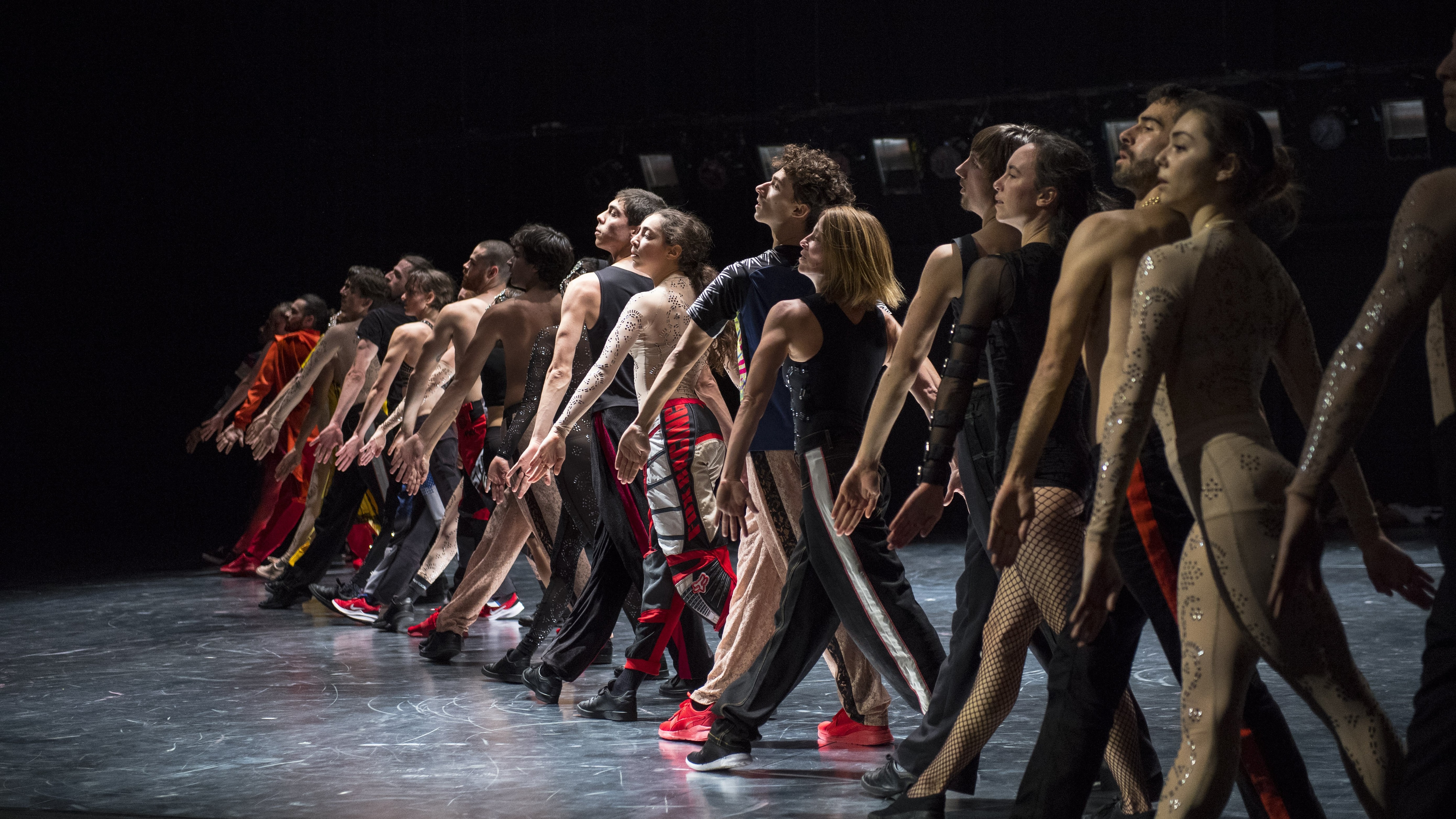 Dancers standing in a line with one leg forward, in Static Shot by Maud le Pladec