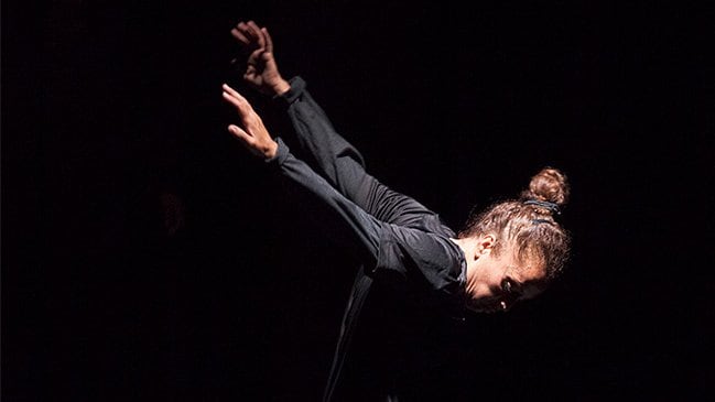 Danseuse sur fond noir, les bras vers l’arrière