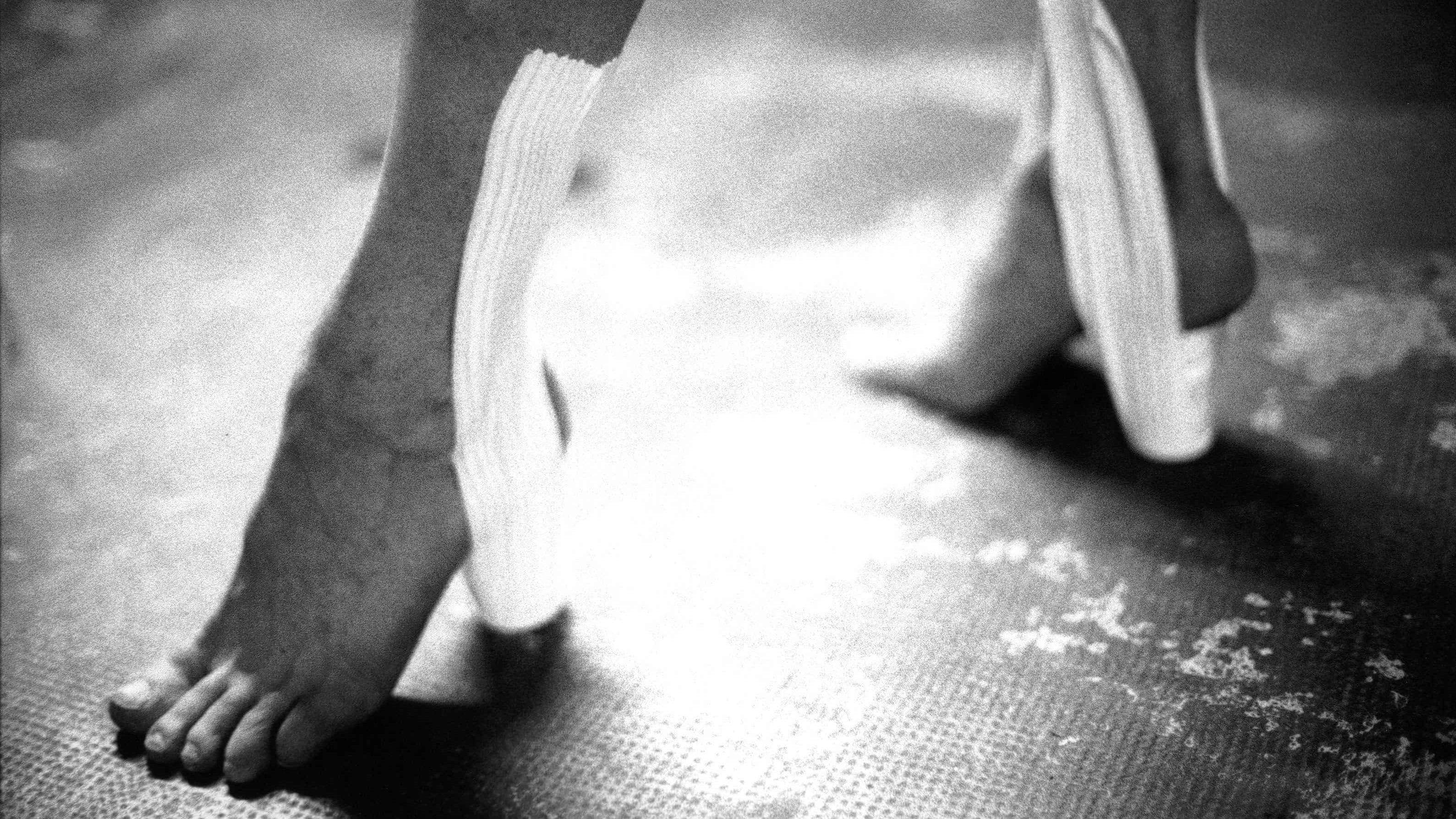 Close-up of bare feet wearing heels made from medical straps, extract from Good Boy