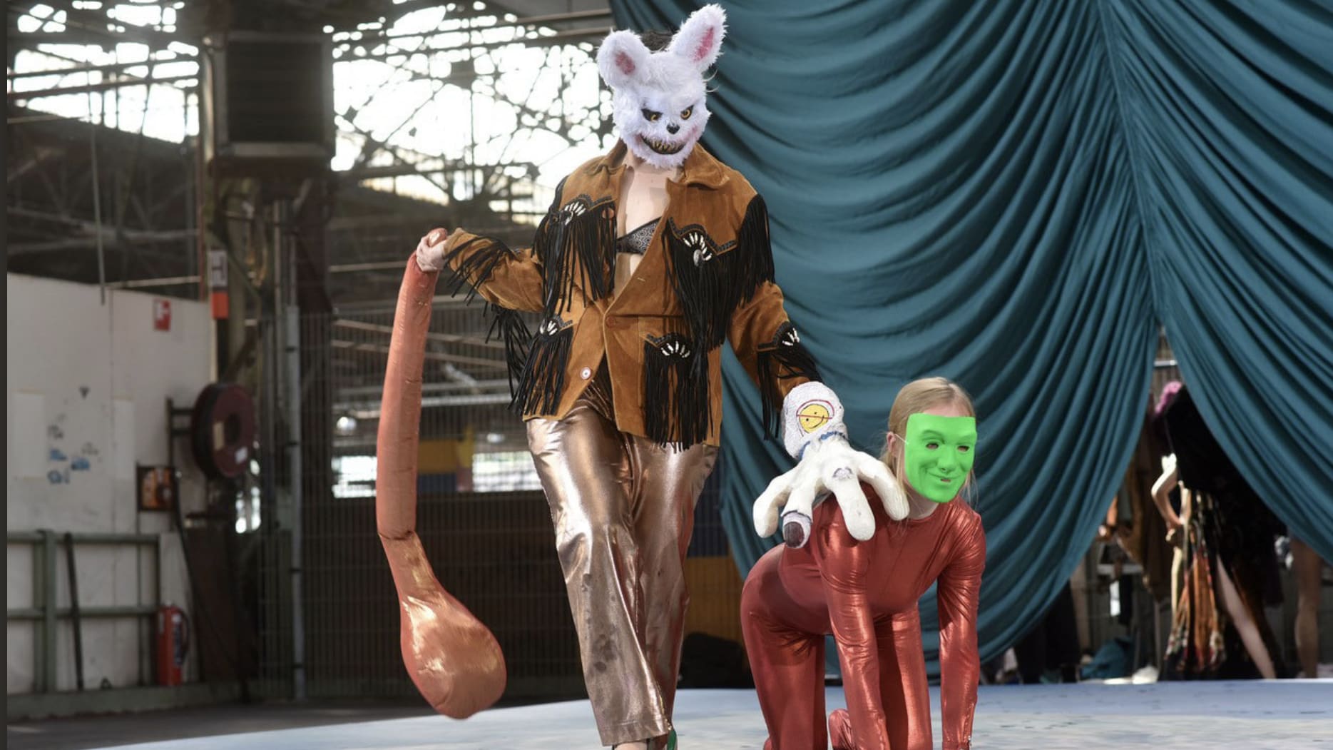 Two masked people on stage, one standing and one on all fours, from Midi Minuit Fantastico